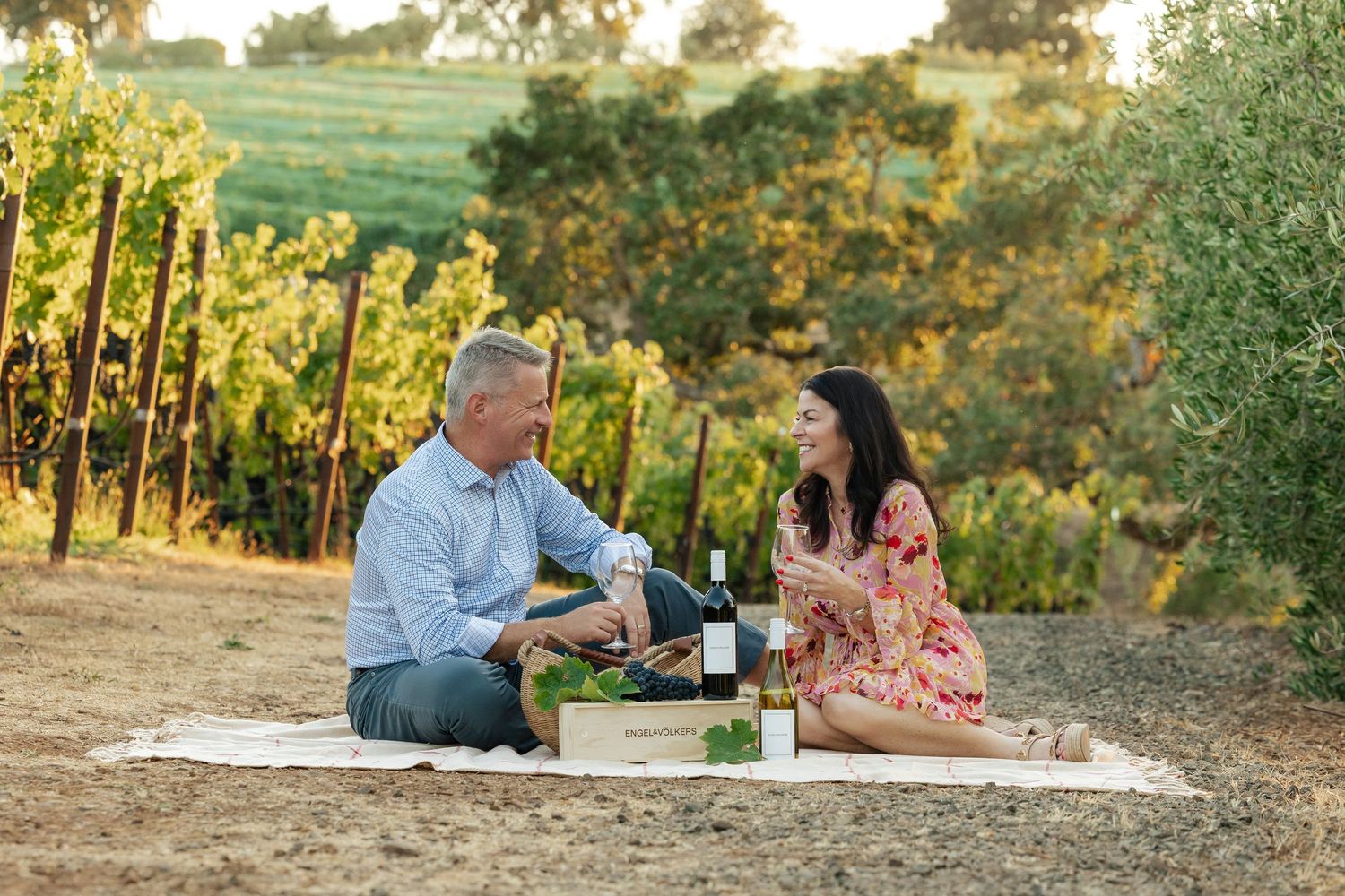 Couple enjoying wine and conversation in a scenic outdoor setting at sunset.
