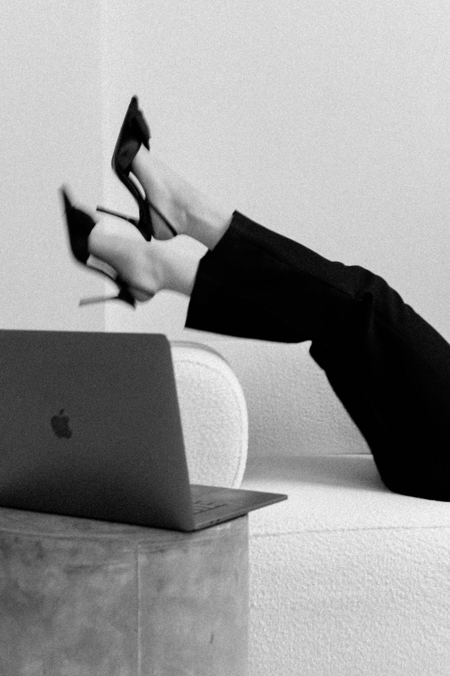 Black high heels shown in motion against a white surface in an artistic sequence.