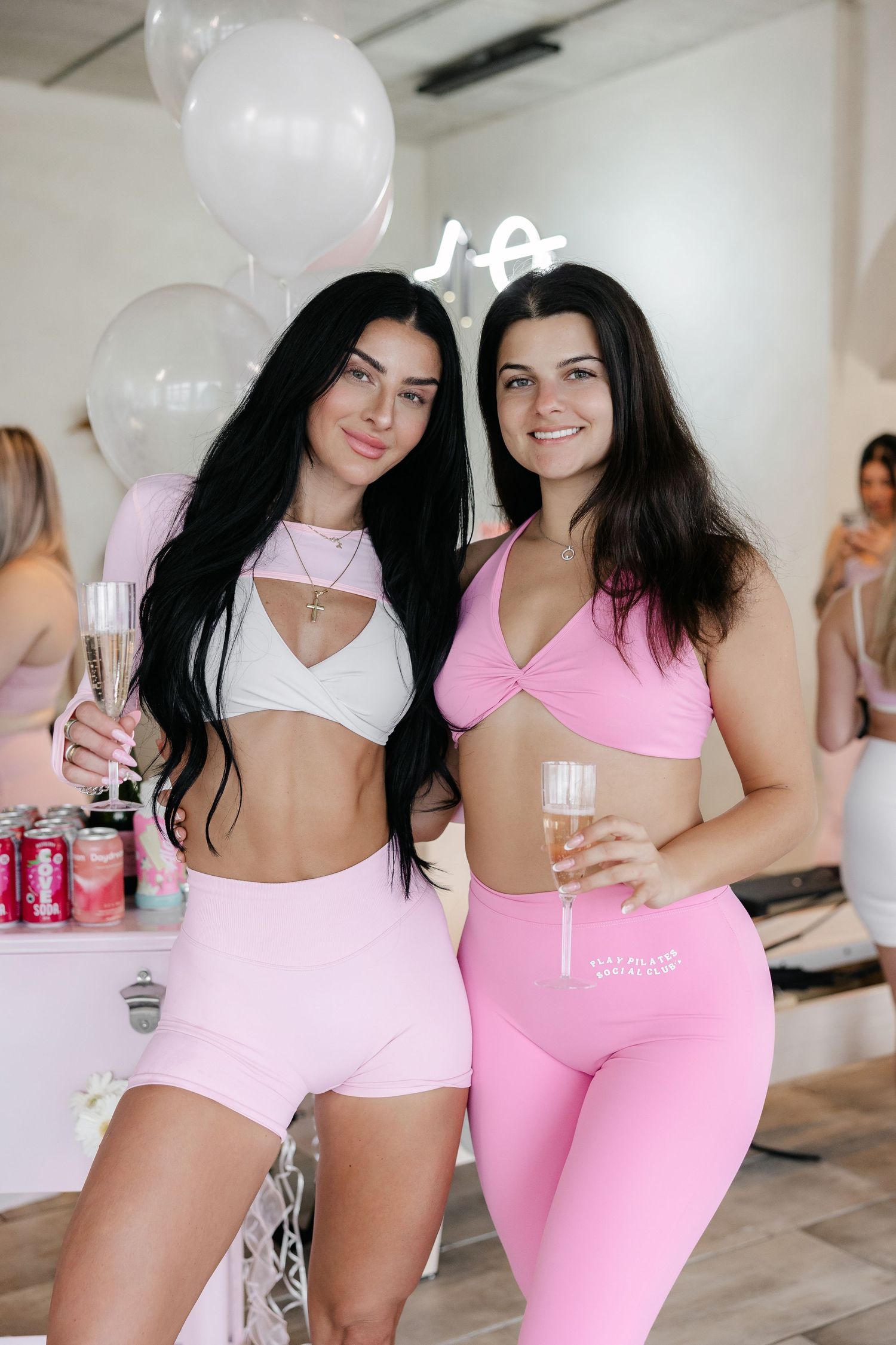Pink-themed fitness celebration with beverages and balloons in a modern studio.