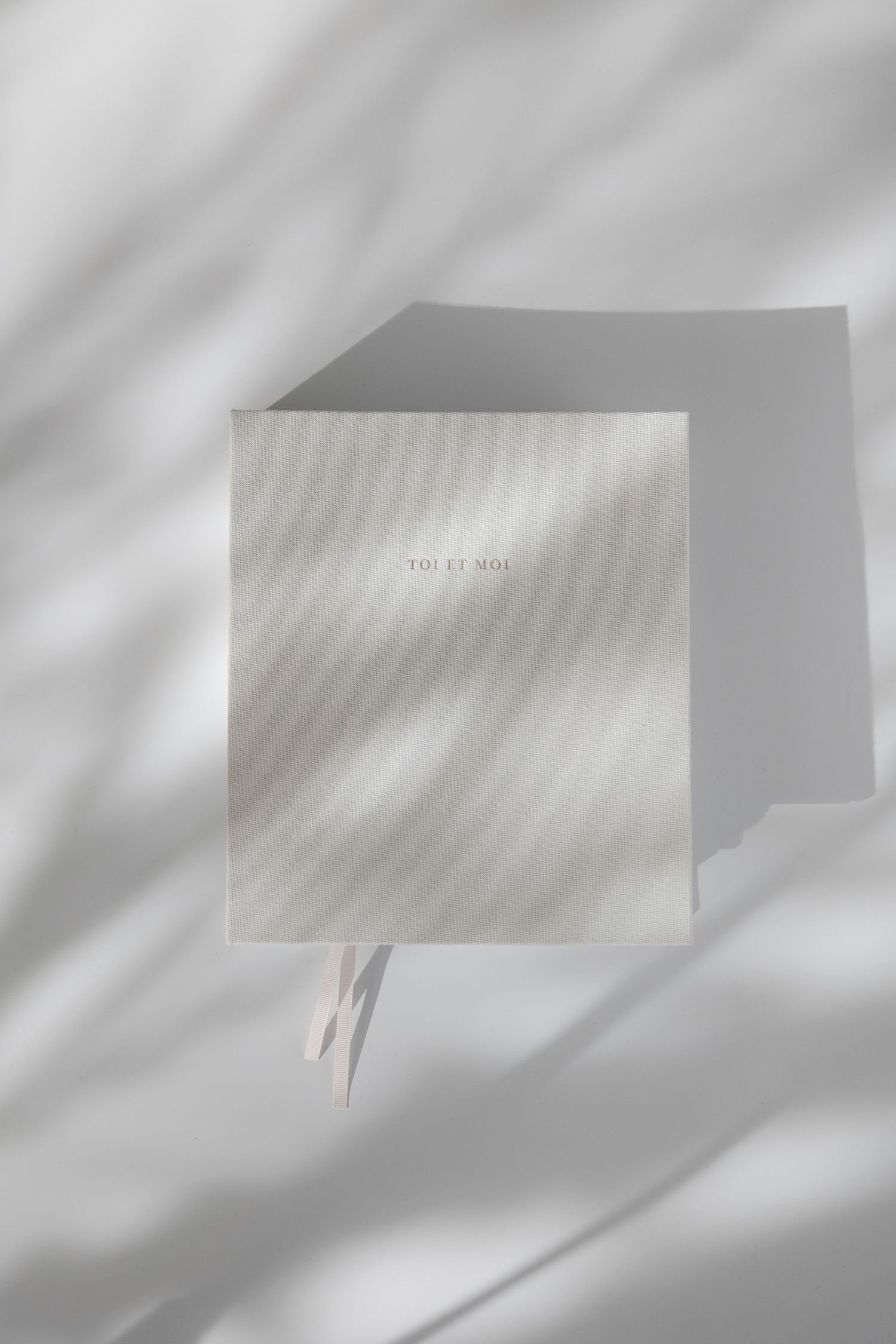 Clean white branded boxes photographed against white wall with dramatic shadow play.