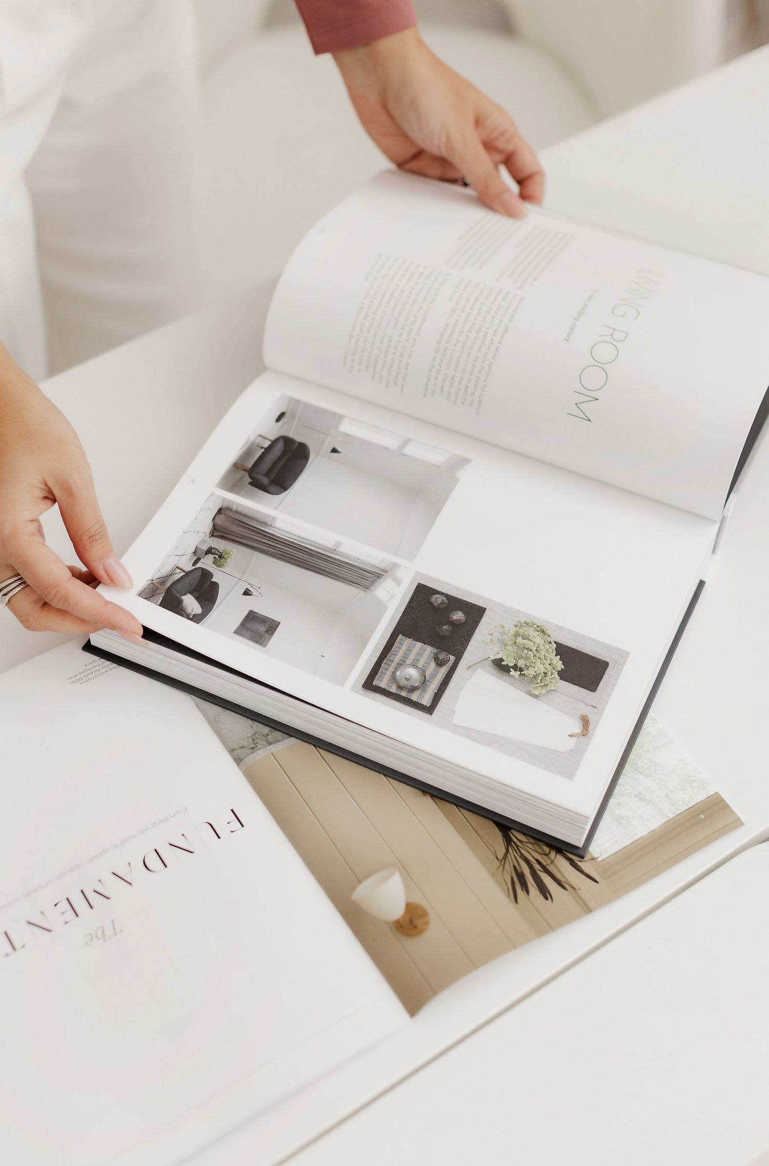 Close up of hands turning pages in luxury product catalog on white desk.