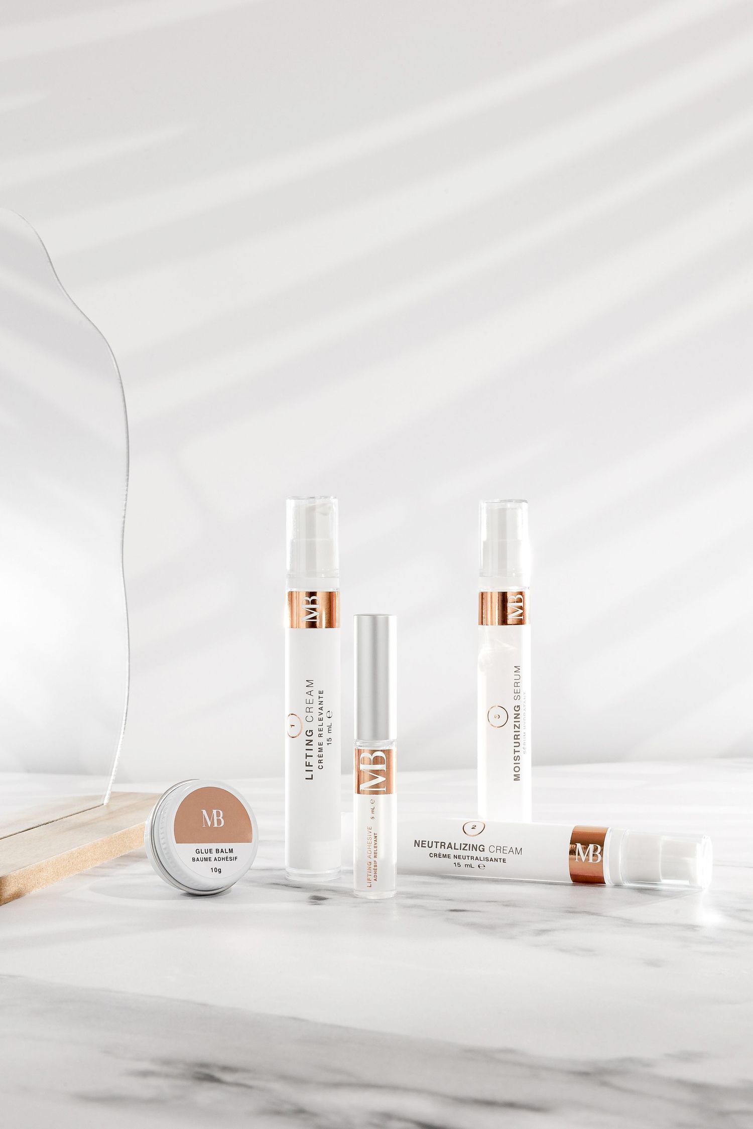 Elegant white cosmetic bottles with rose gold details arranged on marble surface.