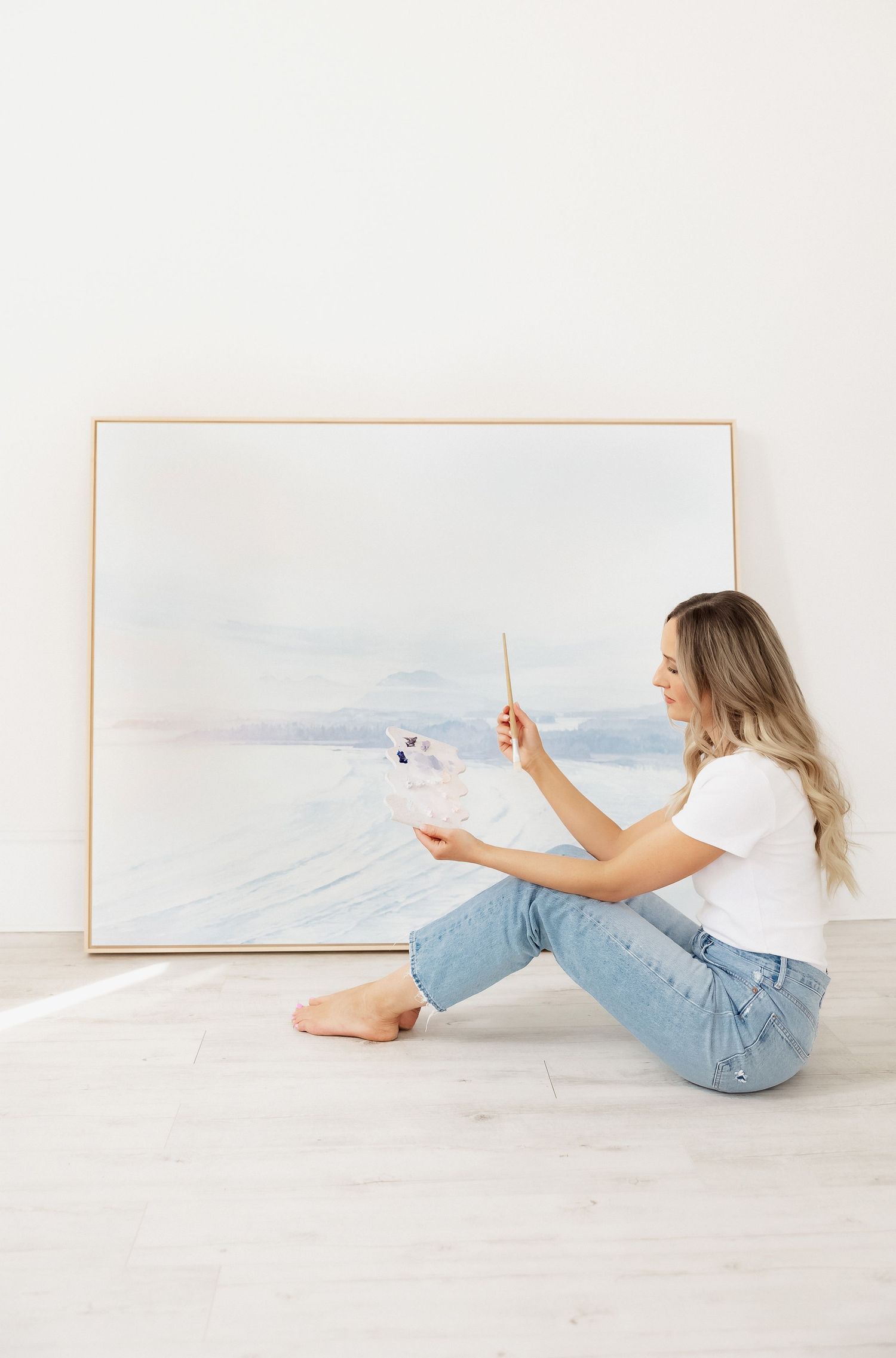 Person in jeans lying on floor taking creative photos of minimal artwork.