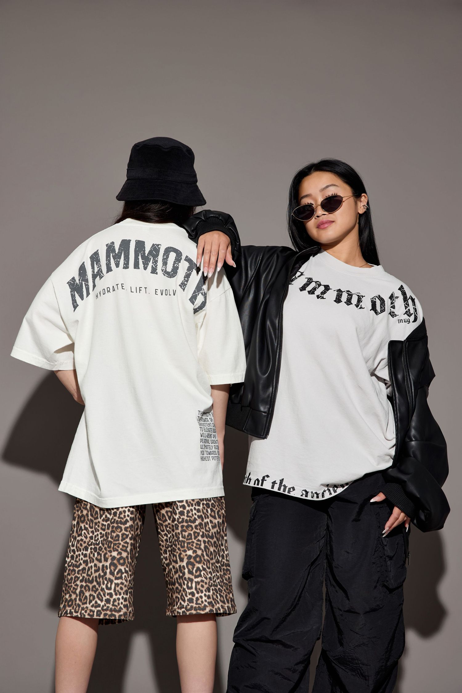 Fashion models wearing white graphic t-shirts and contrasting outfits pose against grey backdrop.