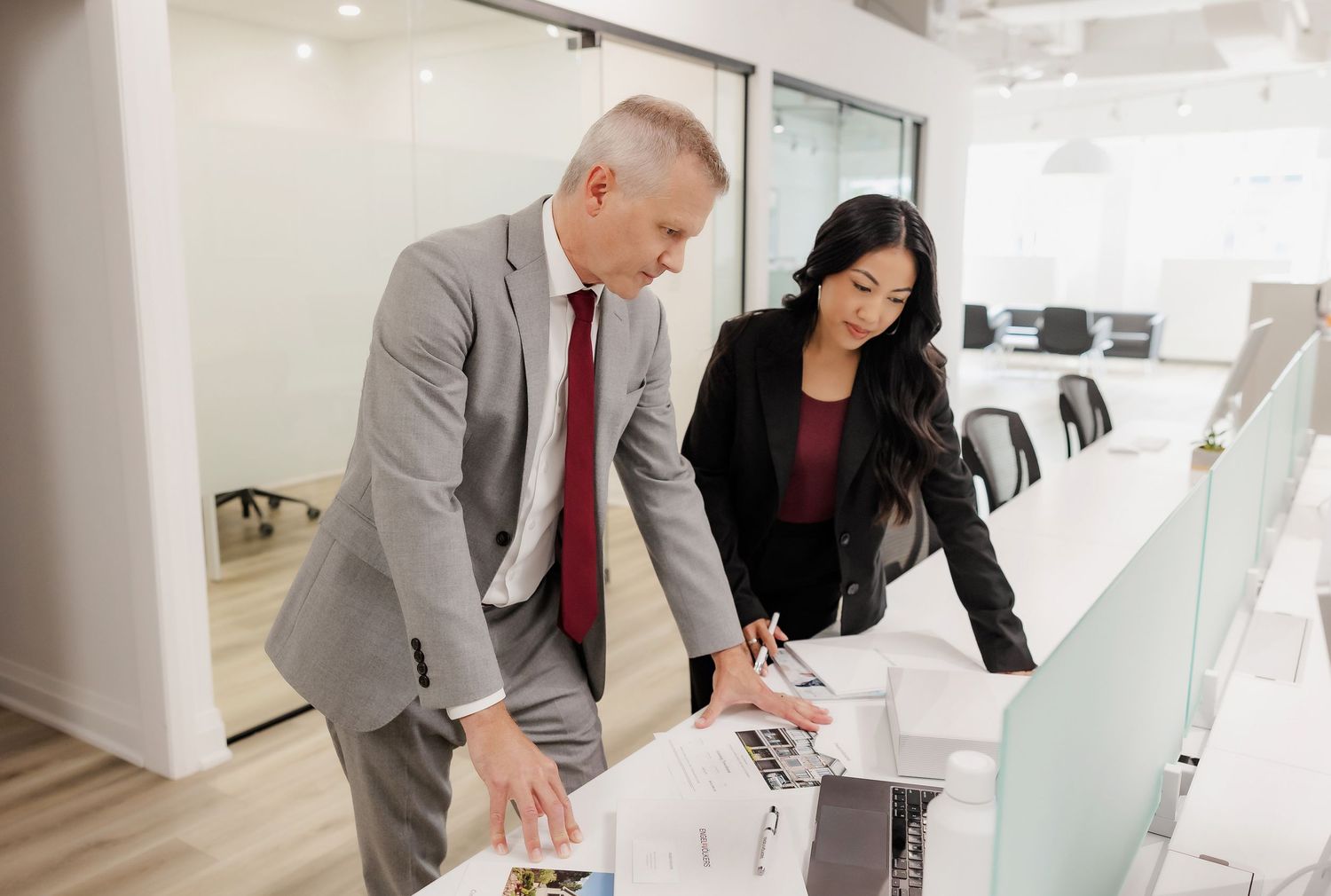 Real estate team discussing documents in modern white office space.