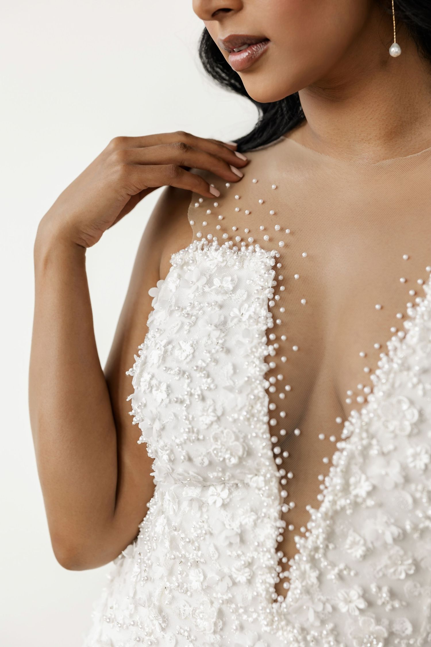 Detailed view of pearl-embellished wedding dress neckline with sheer mesh detailing.