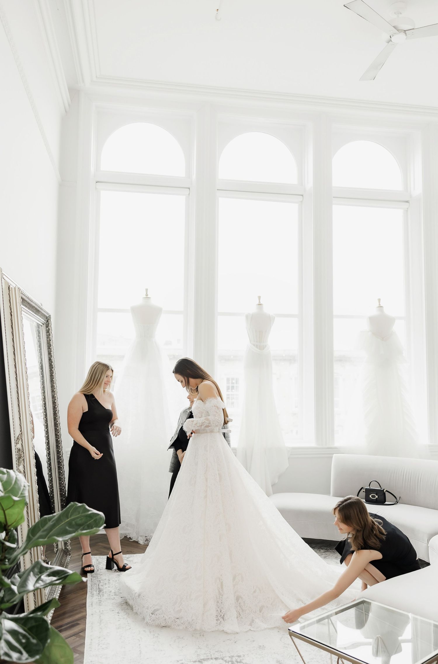 Elegant bridal boutique interior with wedding dress fitting and decorative mirrors.