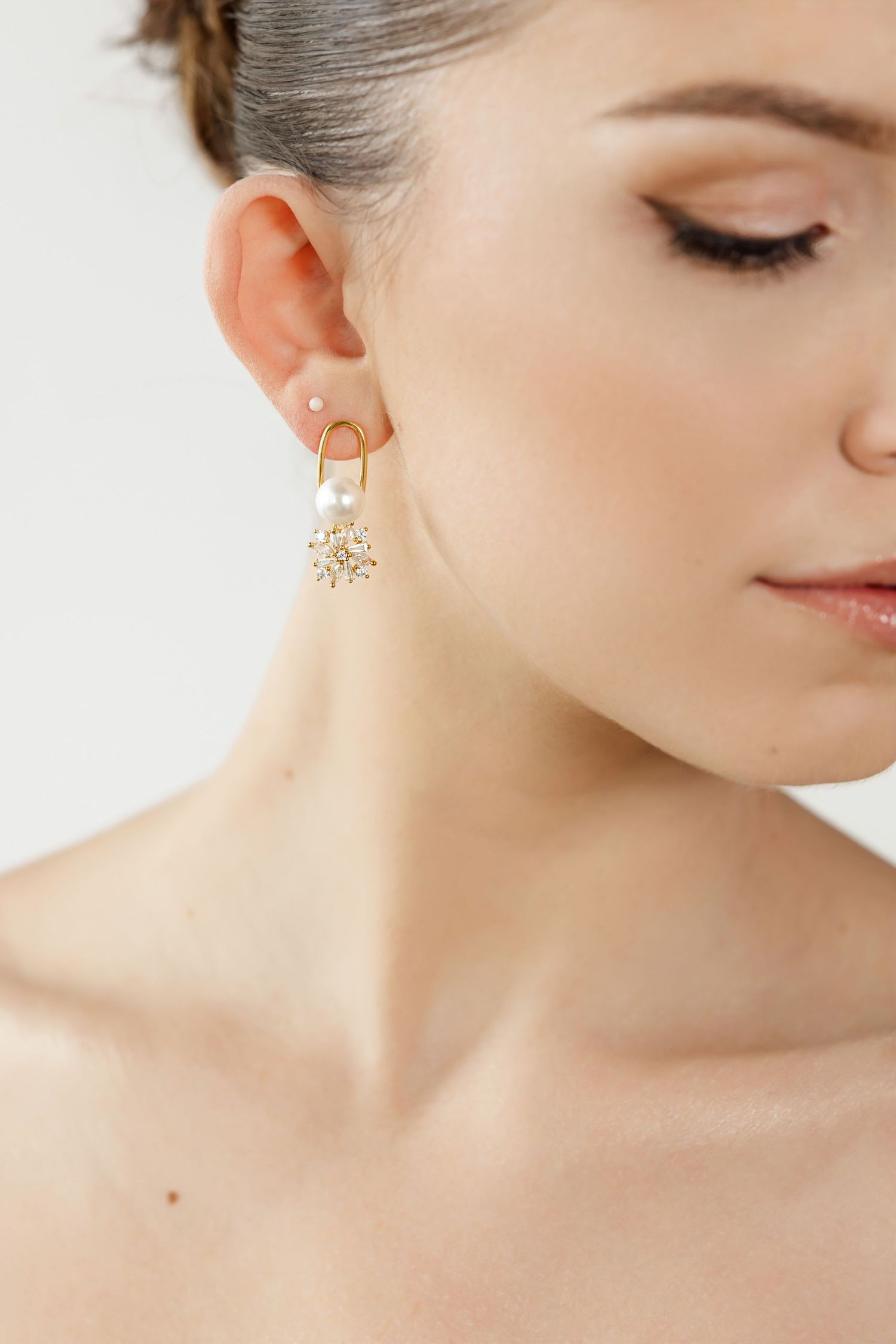 Close-up beauty shot featuring delicate gold star-shaped earring and natural makeup.