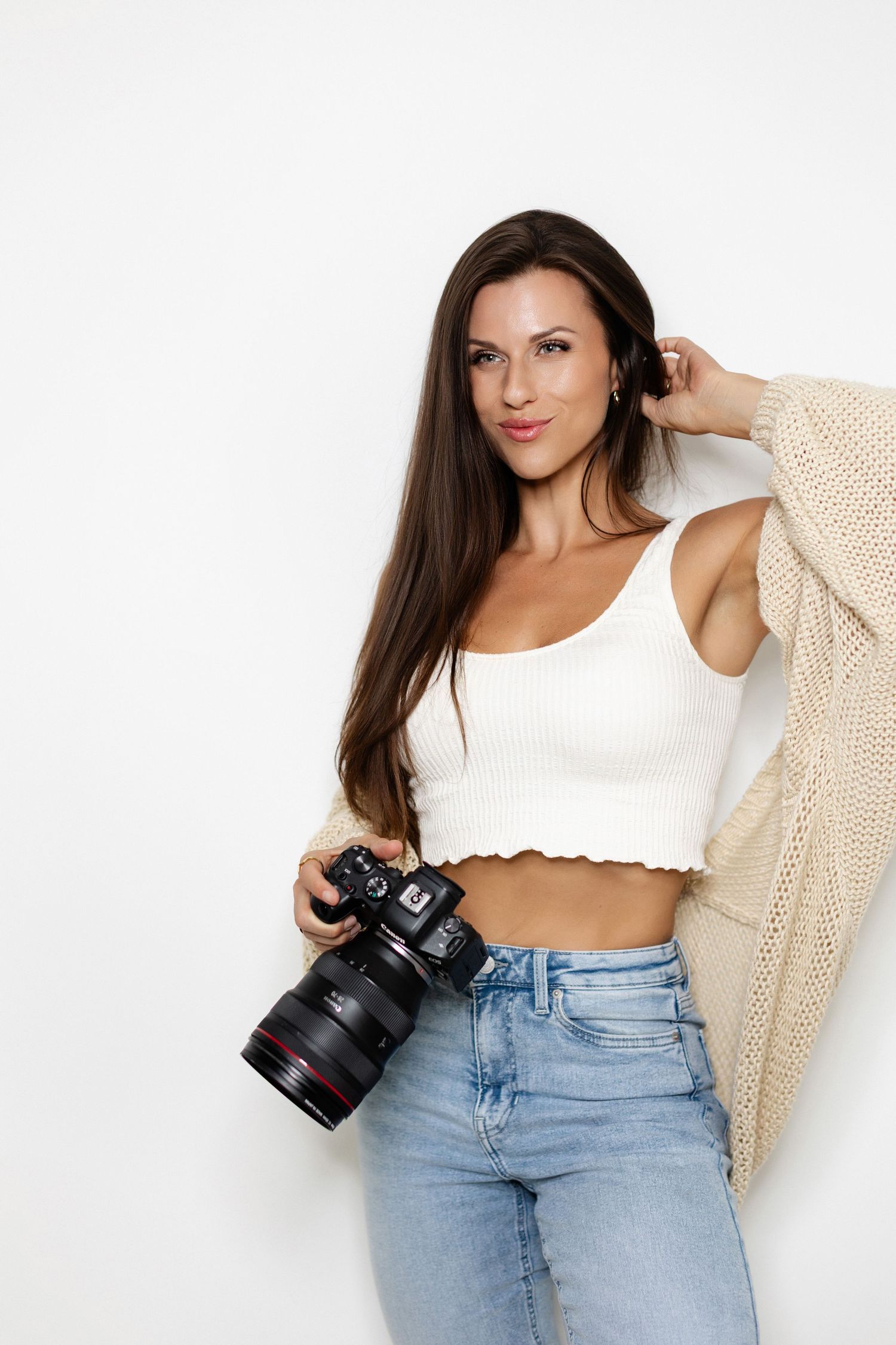 Casual fashion series featuring crop top, cardigan and jeans while holding camera.