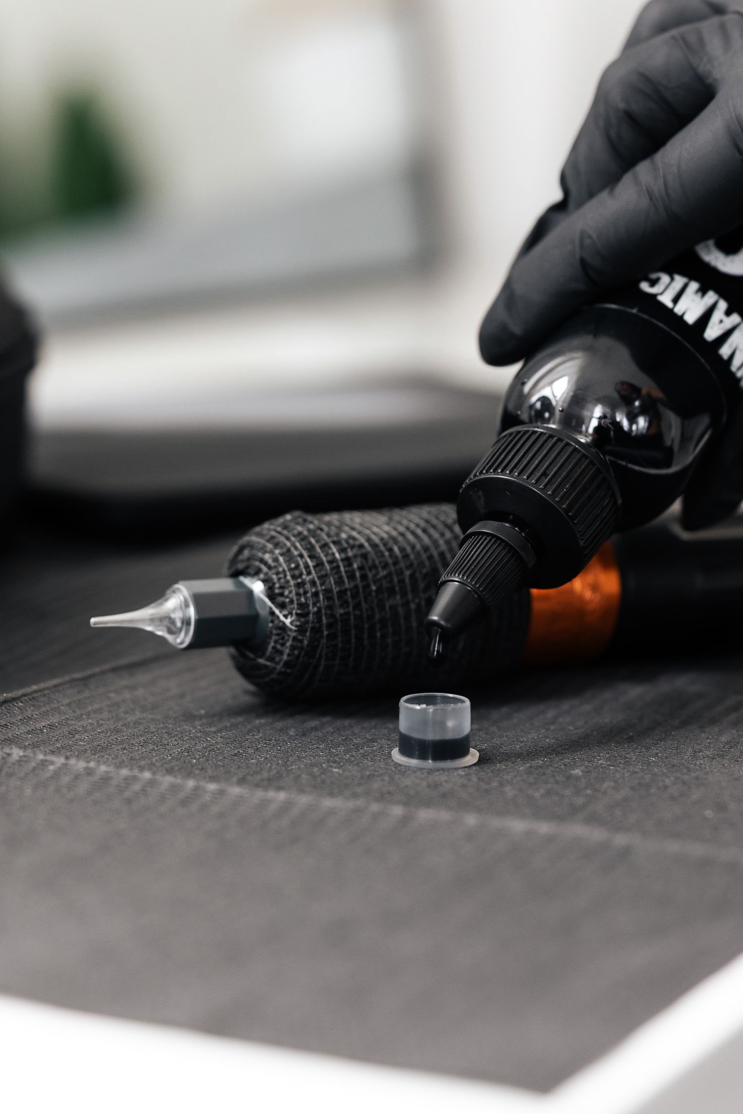 Black gloved hands working with small glass vials on dark surface.