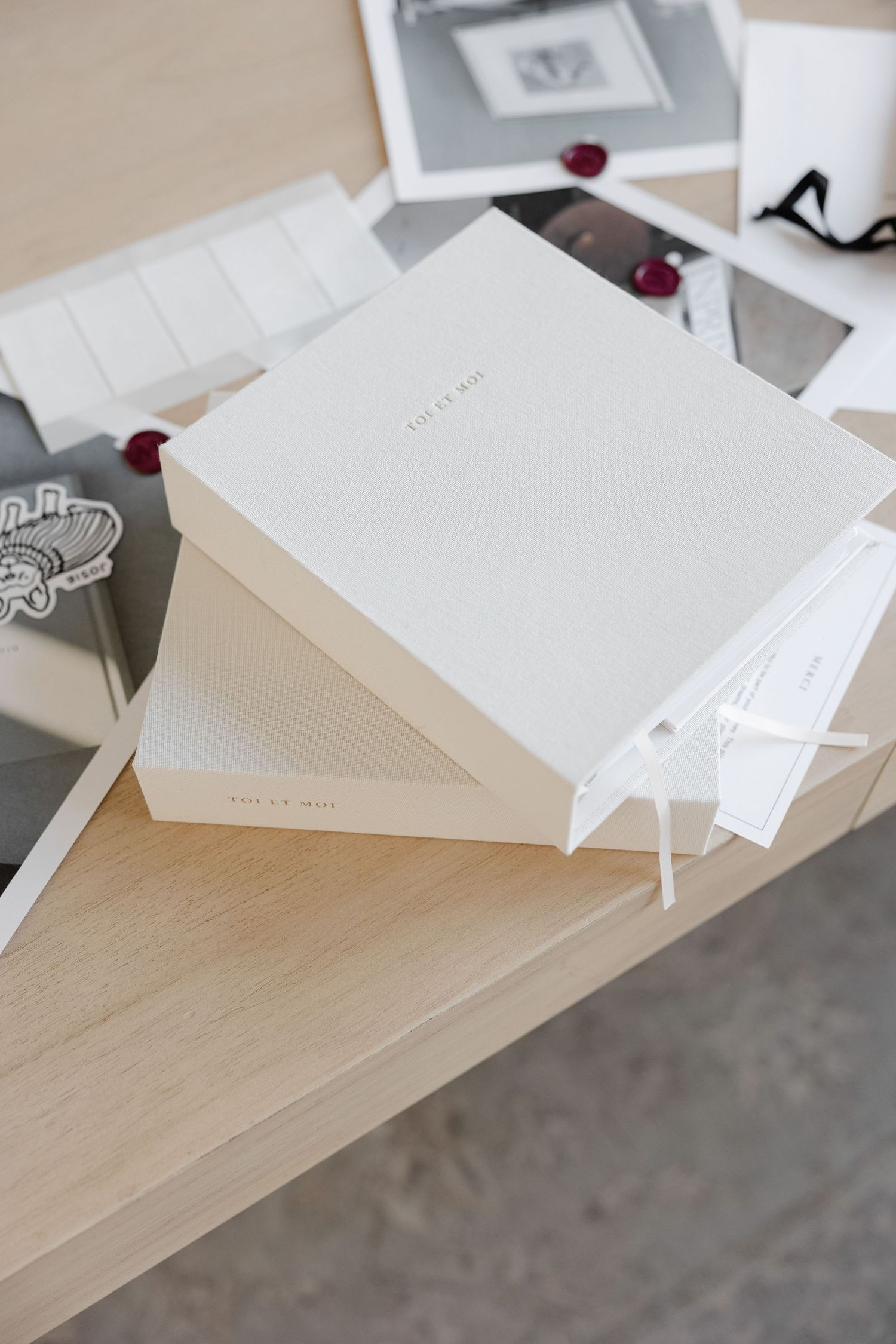 White hardcover books stacked on wooden surface with burgundy accents.