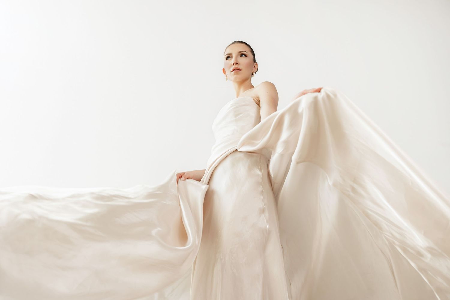 Ethereal bridal gown with dramatic flowing fabric captured in artistic motion.