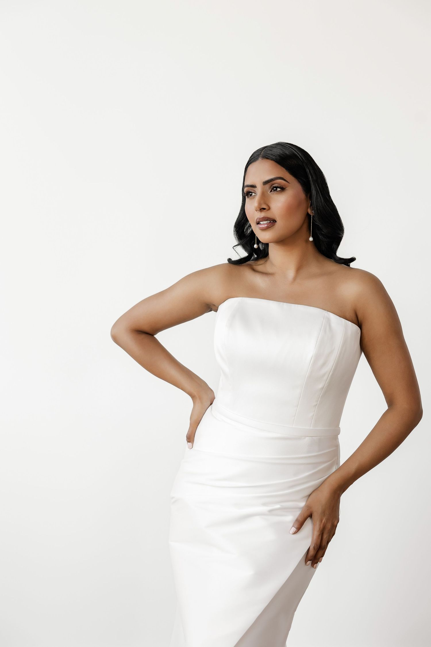 Elegant strapless white wedding dress showcased in minimalist studio setting.