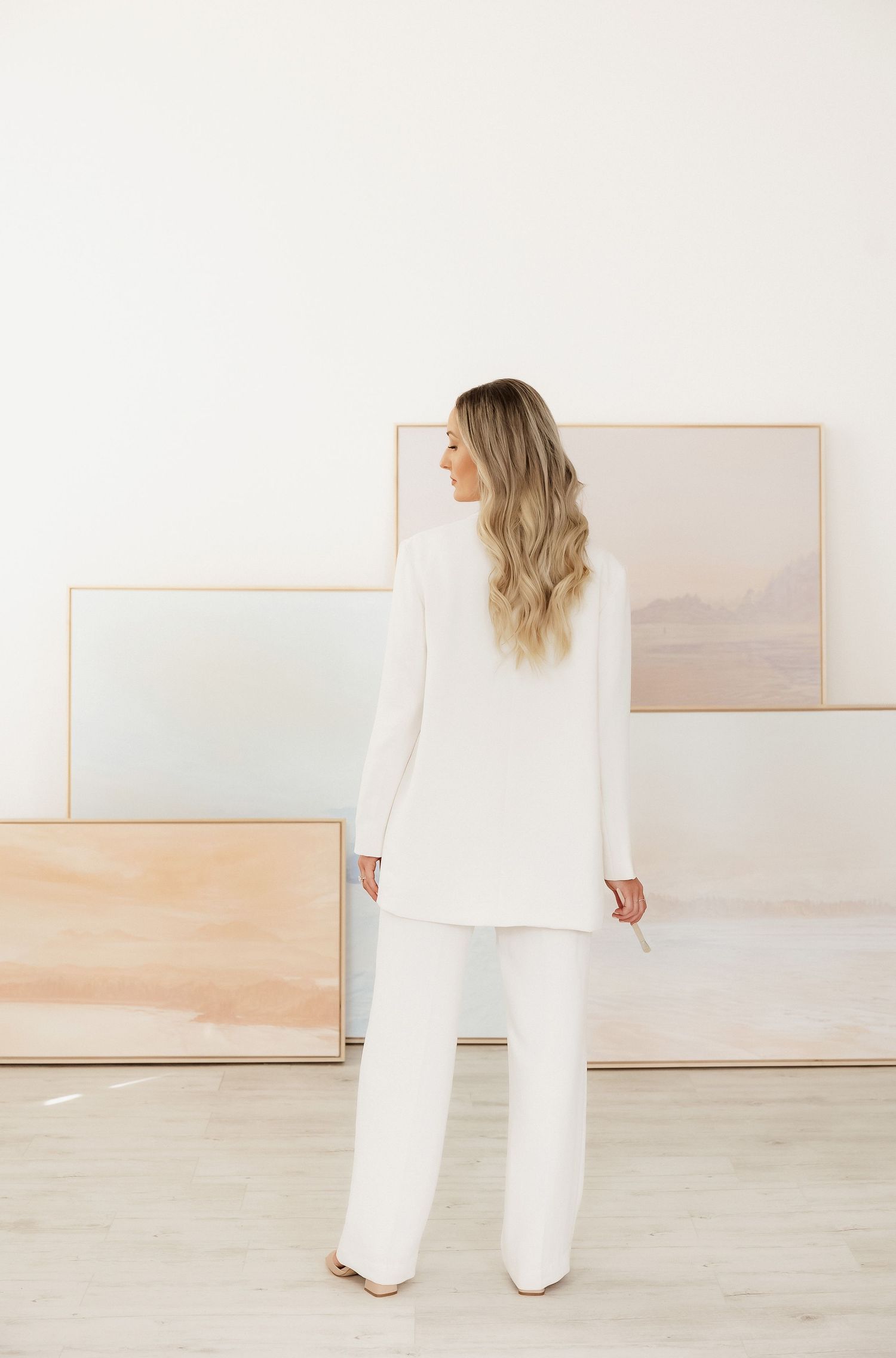 Gallery wall styling with soft pastel abstract artworks in light wooden frames.