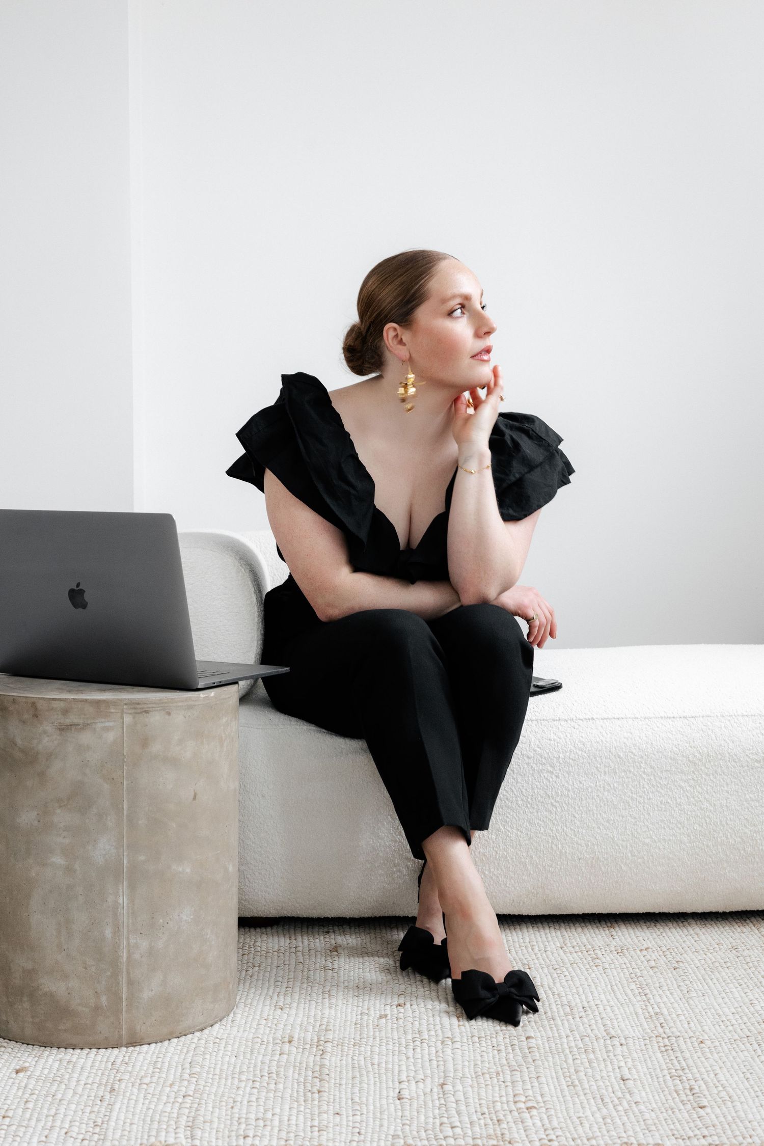 Elegant scene with MacBook on concrete side table and white sofa.