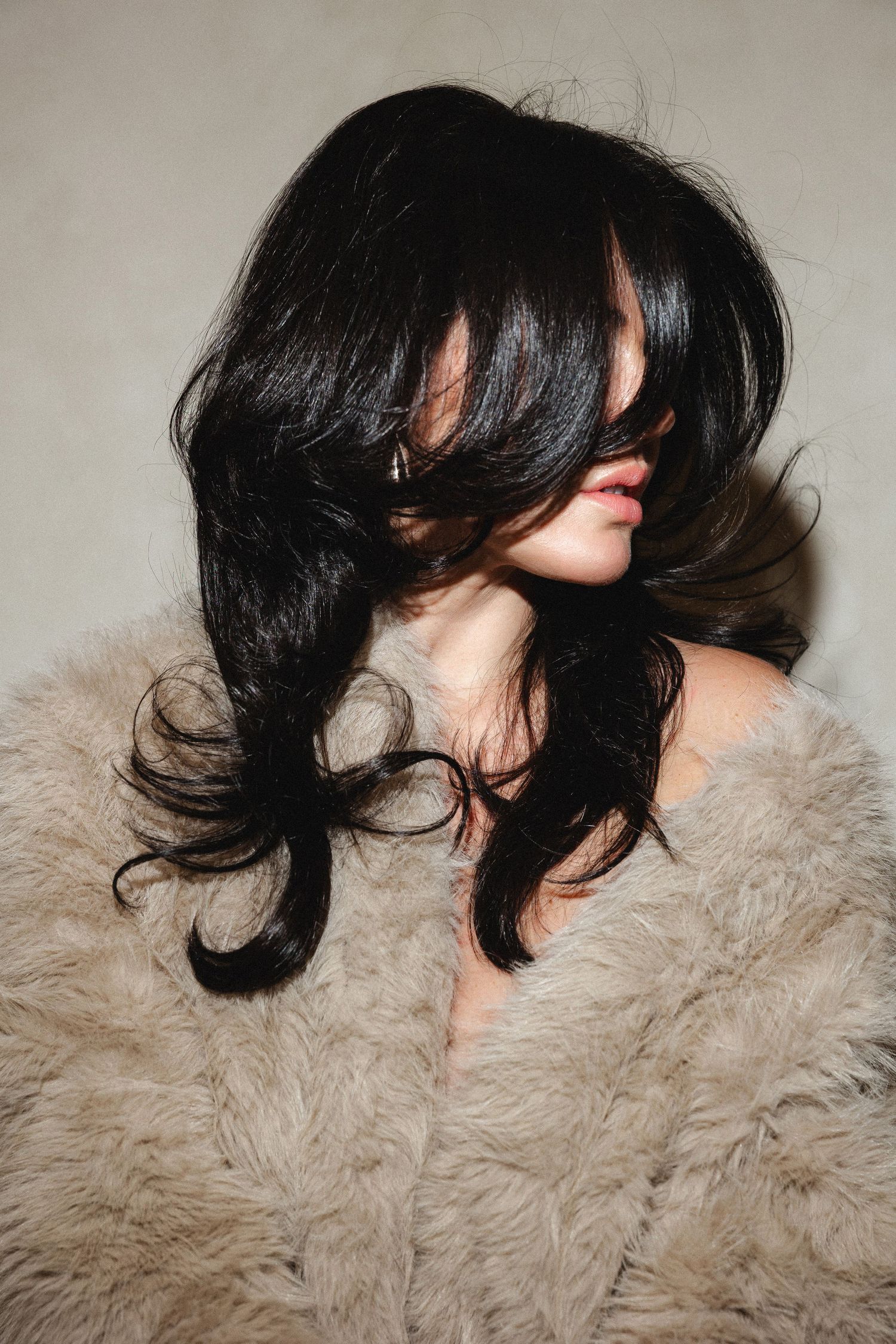 Styled dark hair displayed against beige furry background.