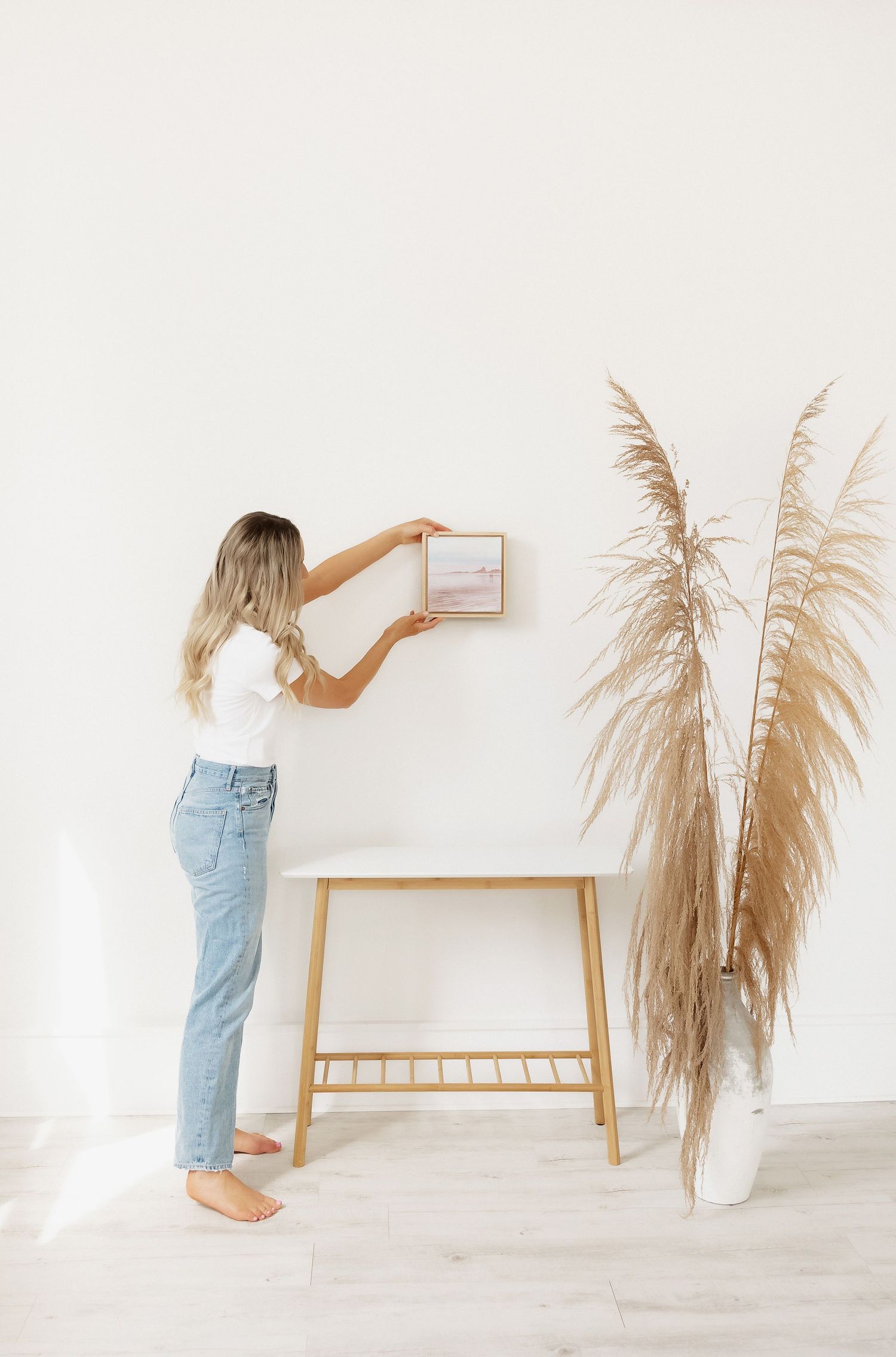 Styling scene with pampas grass and minimal decor against white wall.