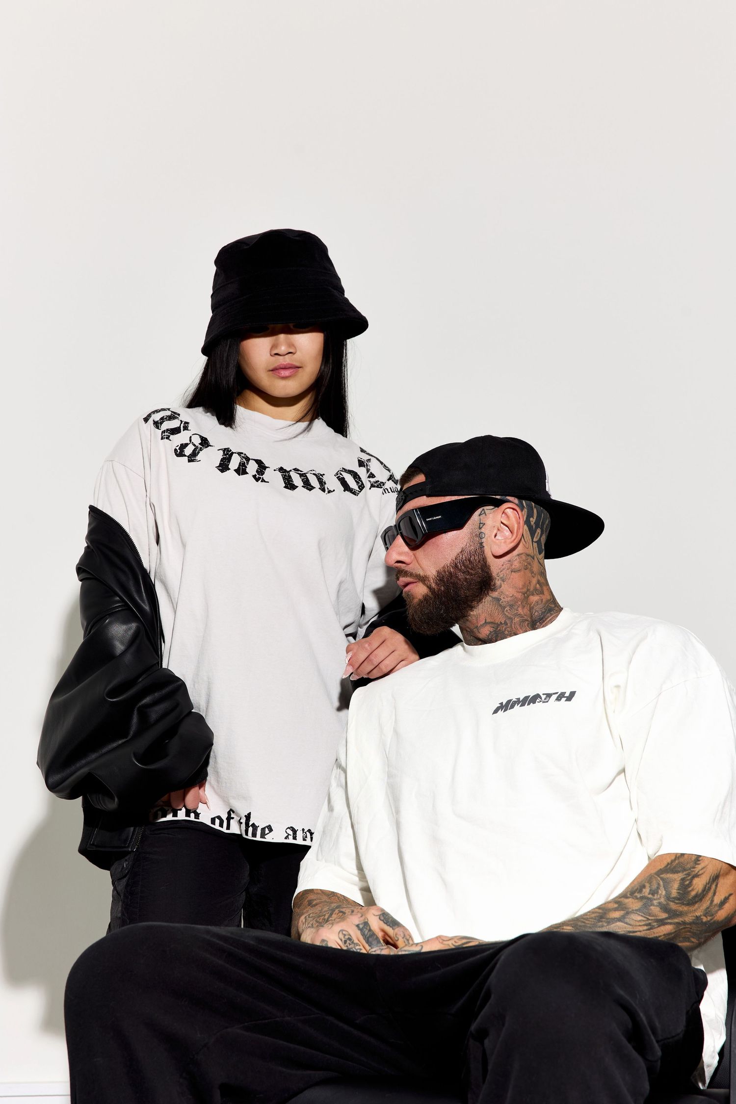 Models in black and white streetwear posing against white background.