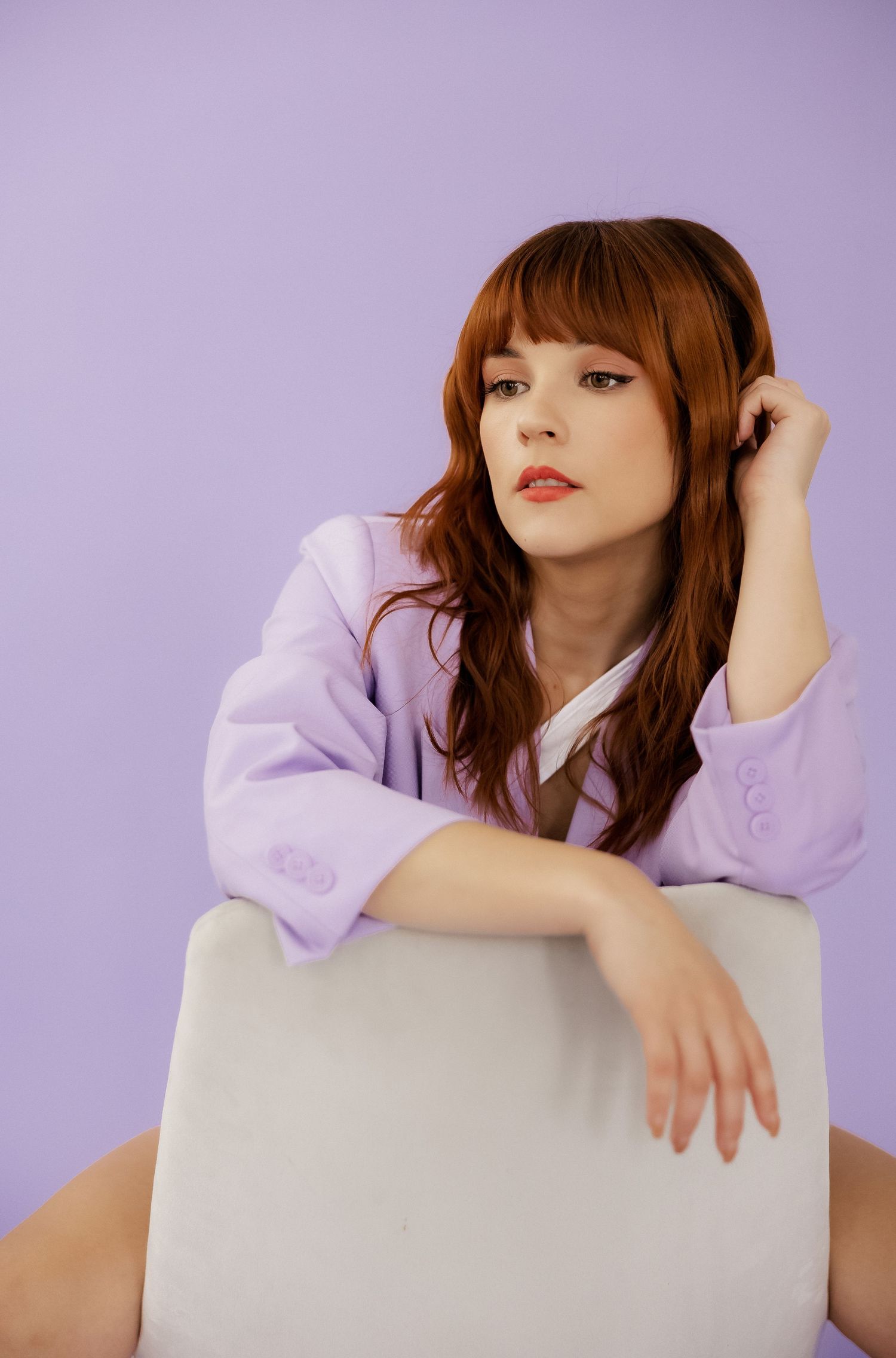 Fashion portrait series on white cube against purple backdrop showing relaxed poses.