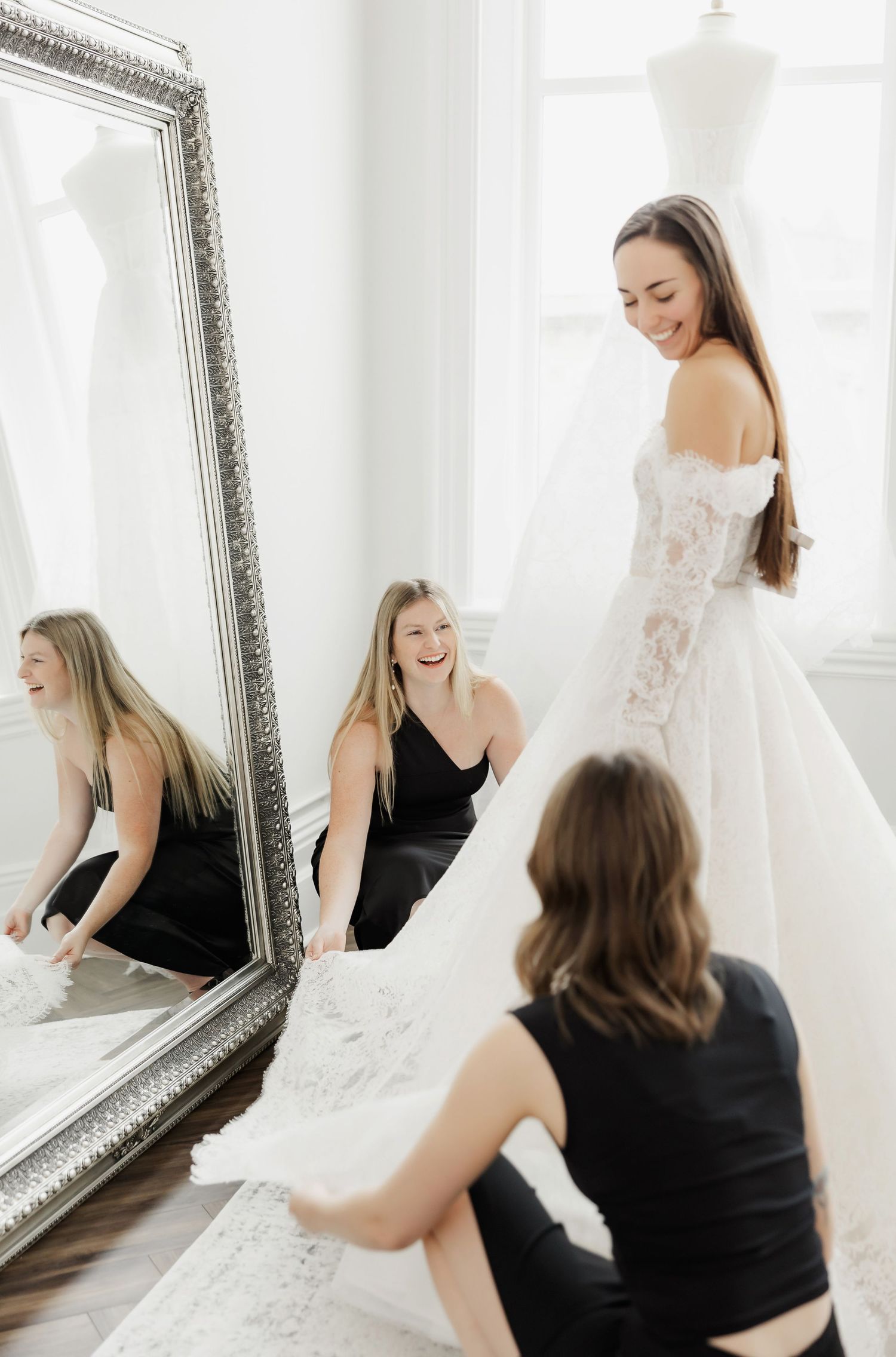 Bridal fitting session with ornate mirror and wedding dress preparations.