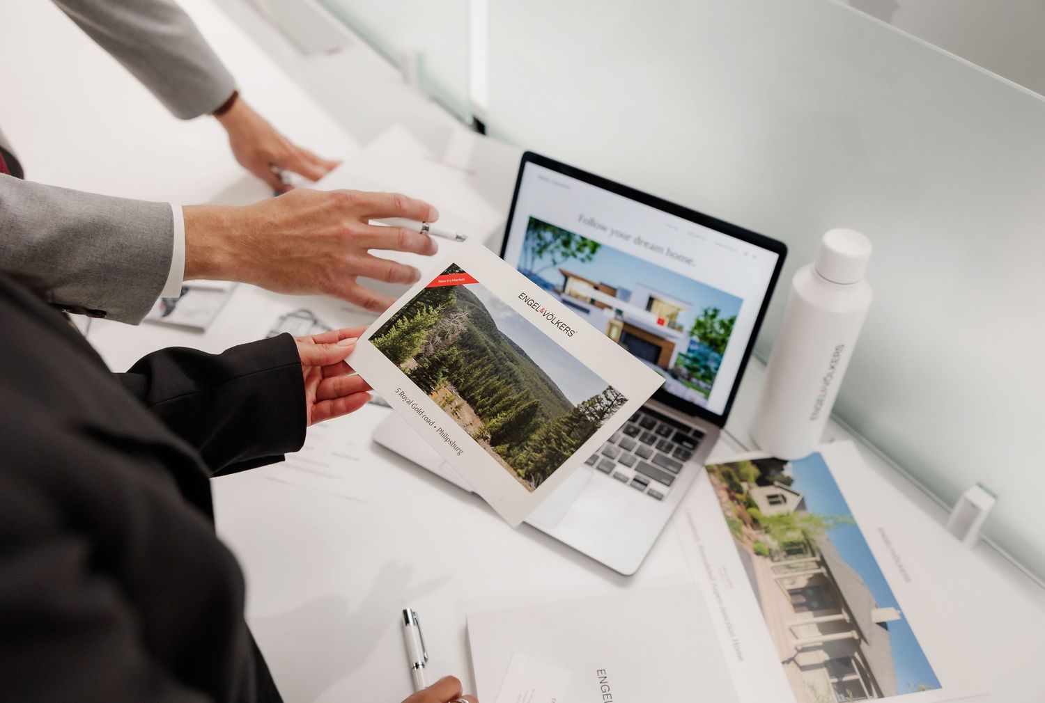 Business professionals reviewing property listings and data on laptop computer.