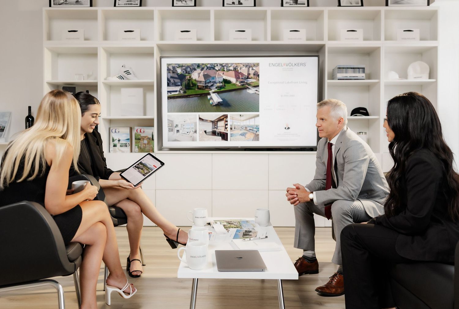 Group of people in business attire having a meeting around a modern white conference table.