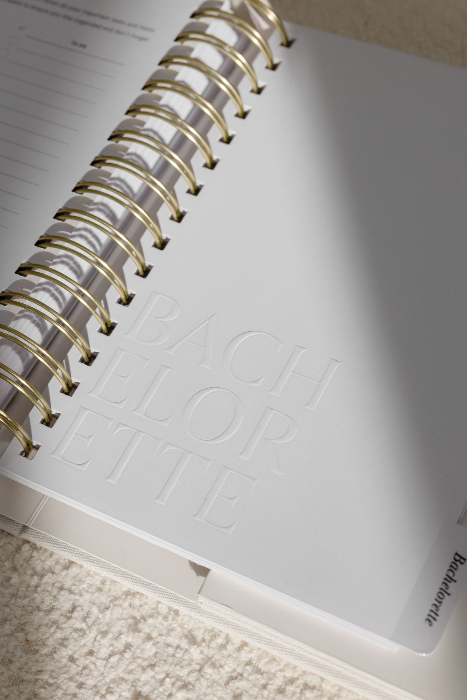 Spiral-bound notebook with embossed text detail shown in close-up.