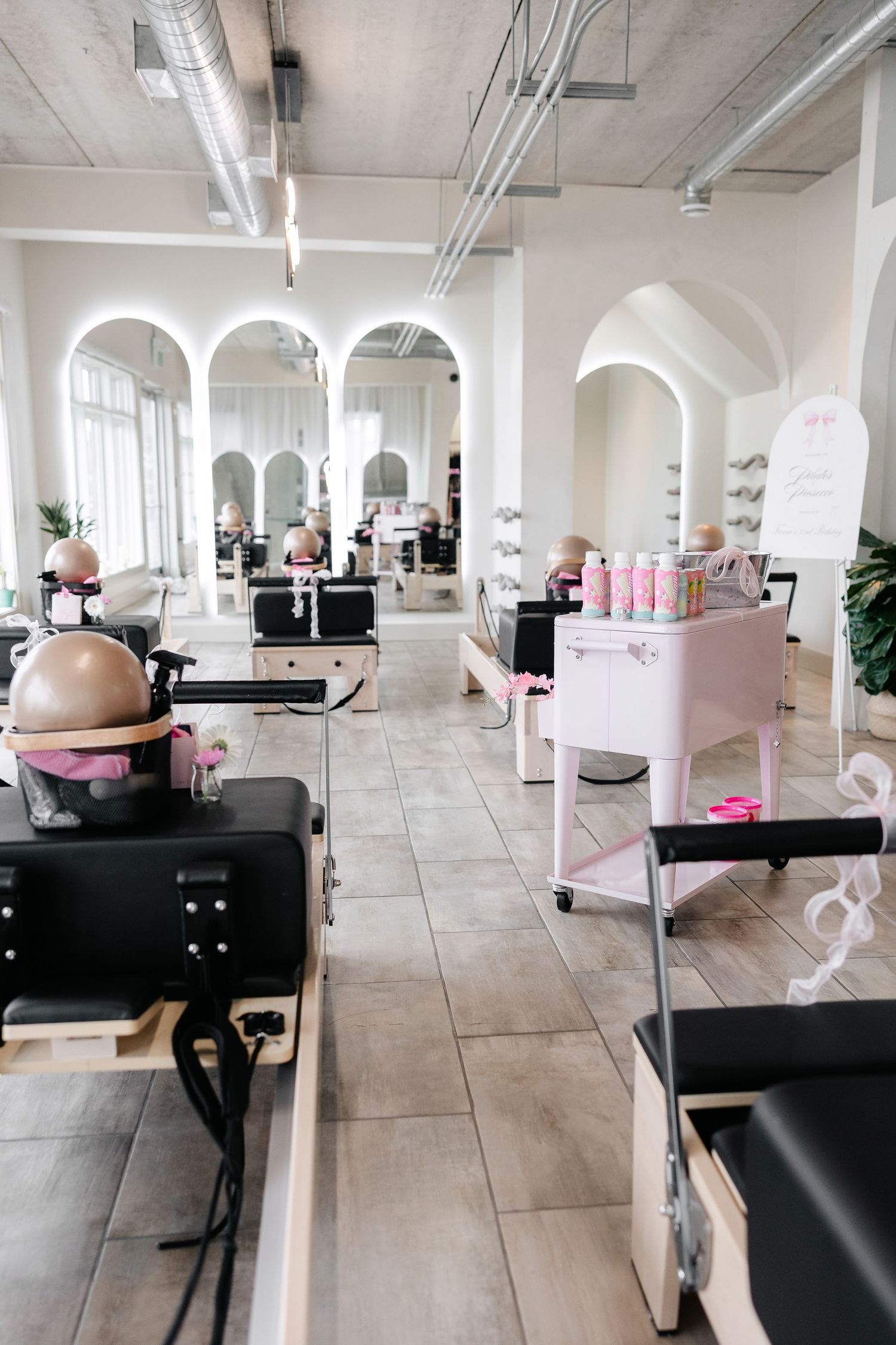 Bright contemporary pilates studio with black reformer machines and pink decor.
