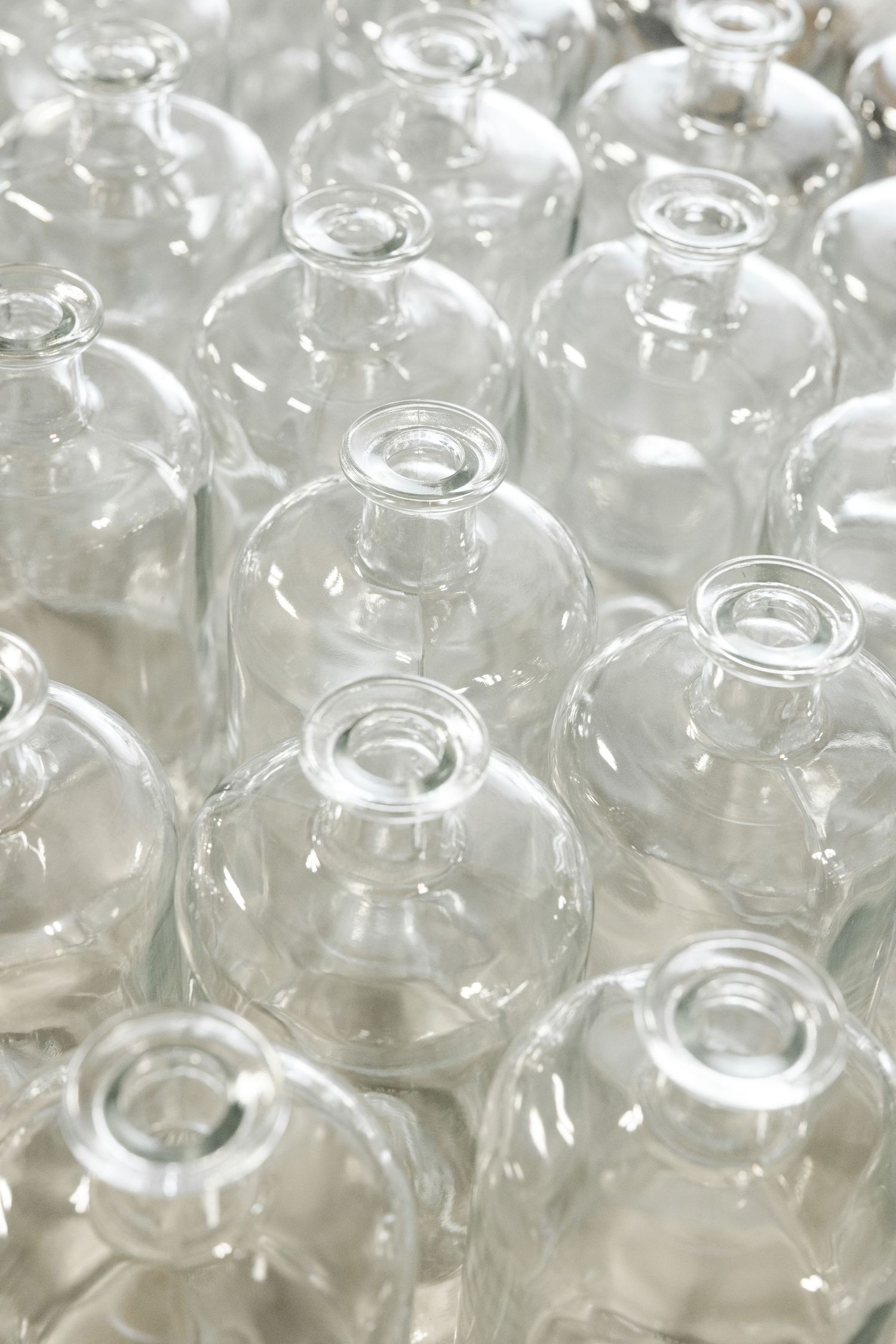 Rows of empty glass bottles arranged in uniform pattern showing transparent surfaces and rims.