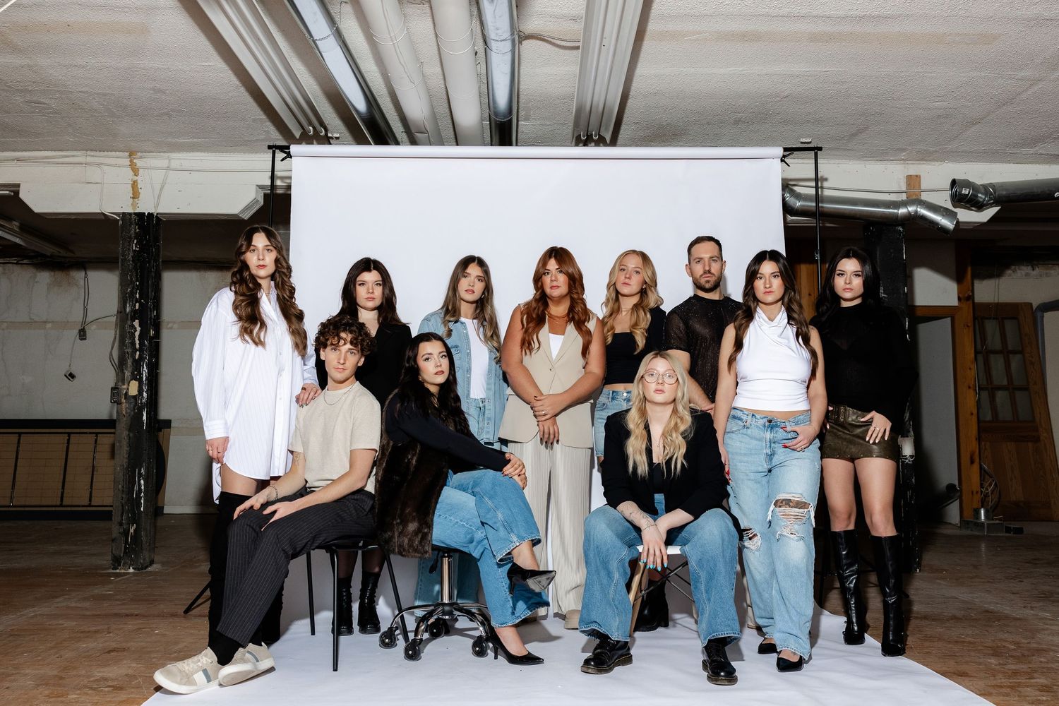 Group fashion photoshoot with models in coordinated denim and white outfits.