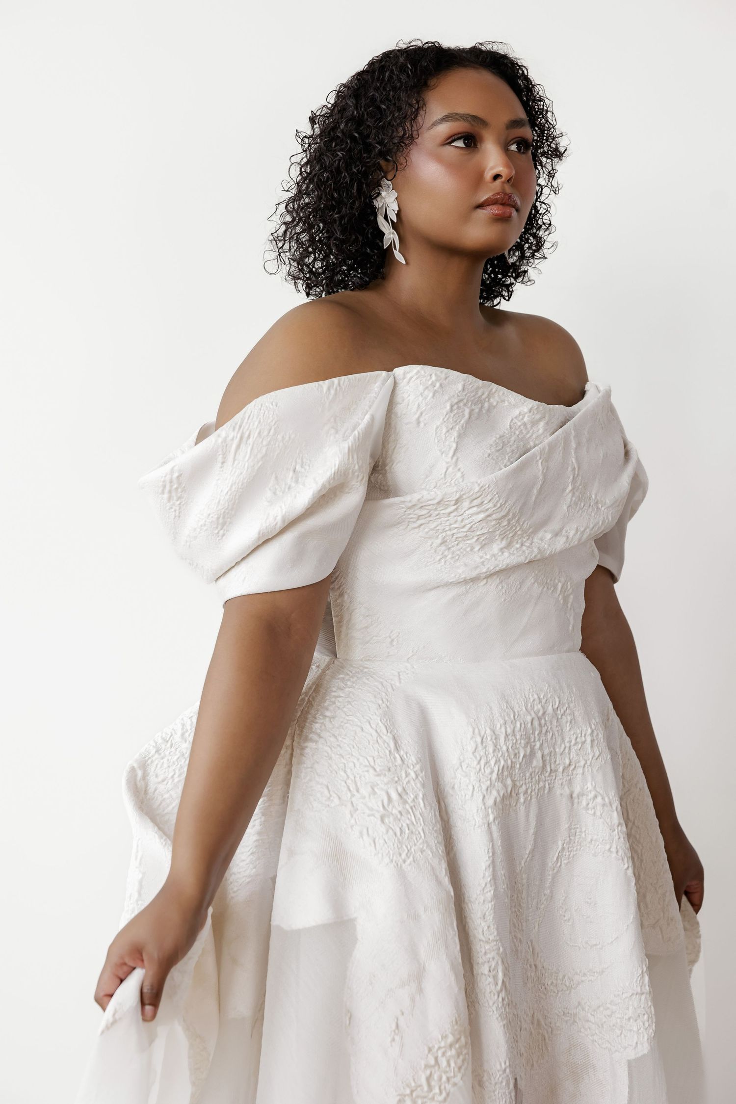 Off-shoulder wedding dress with textured fabric and flowing silhouette shown in multiple angles.