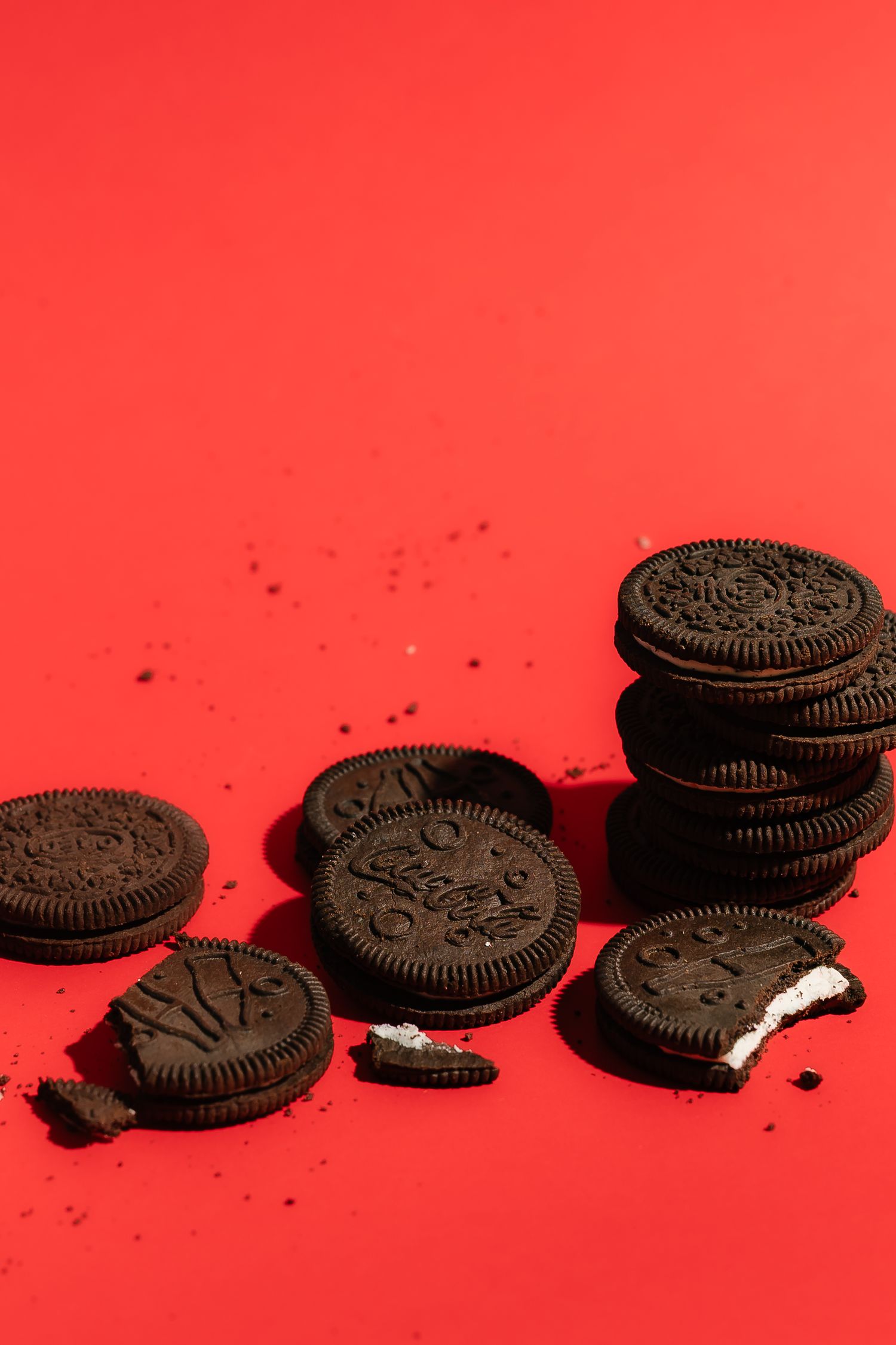 Row of Oreo cookies casting dramatic shadows on vibrant red background.