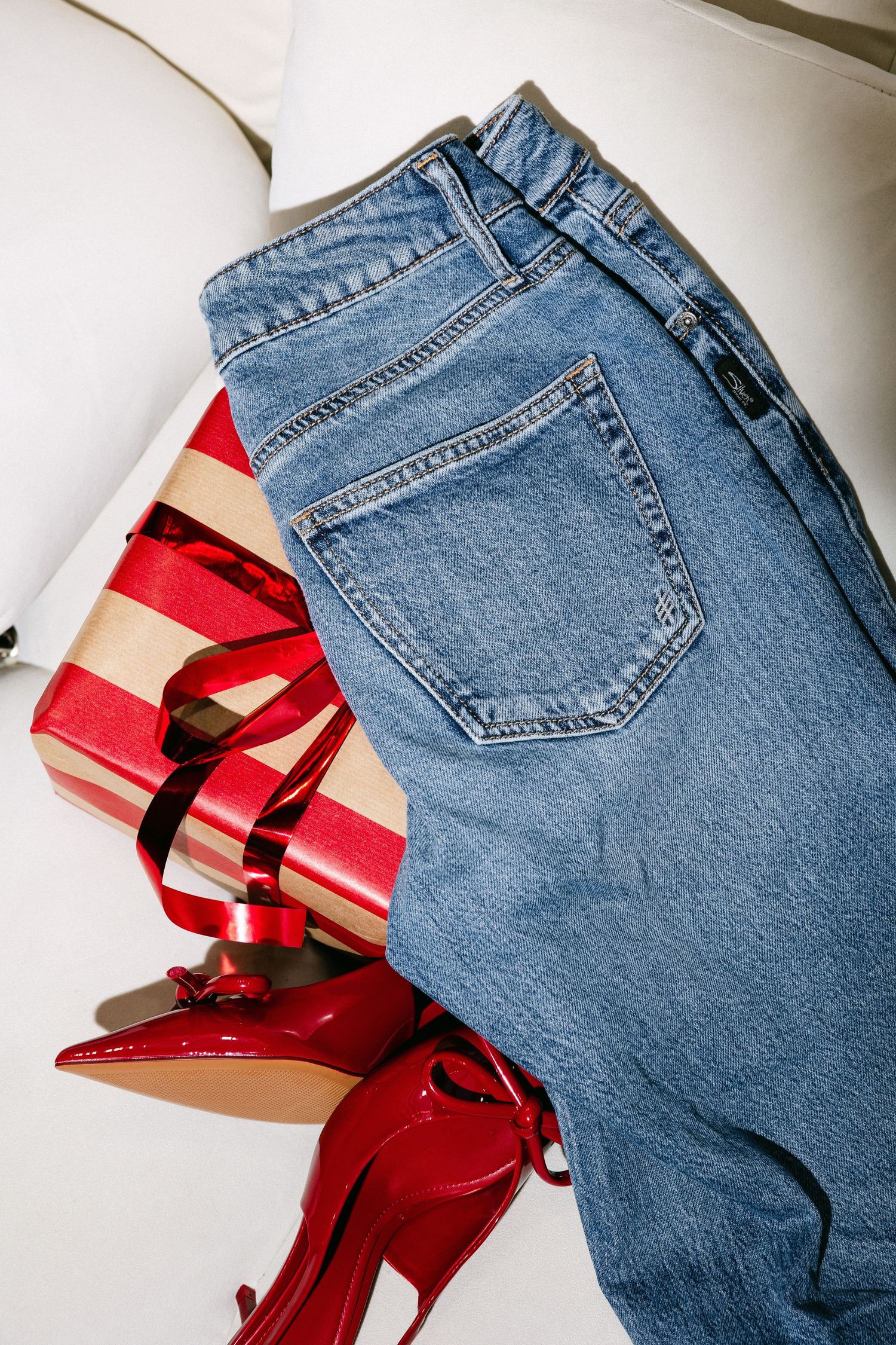 Contrast of blue denim jeans and bright red accessories on white background.
