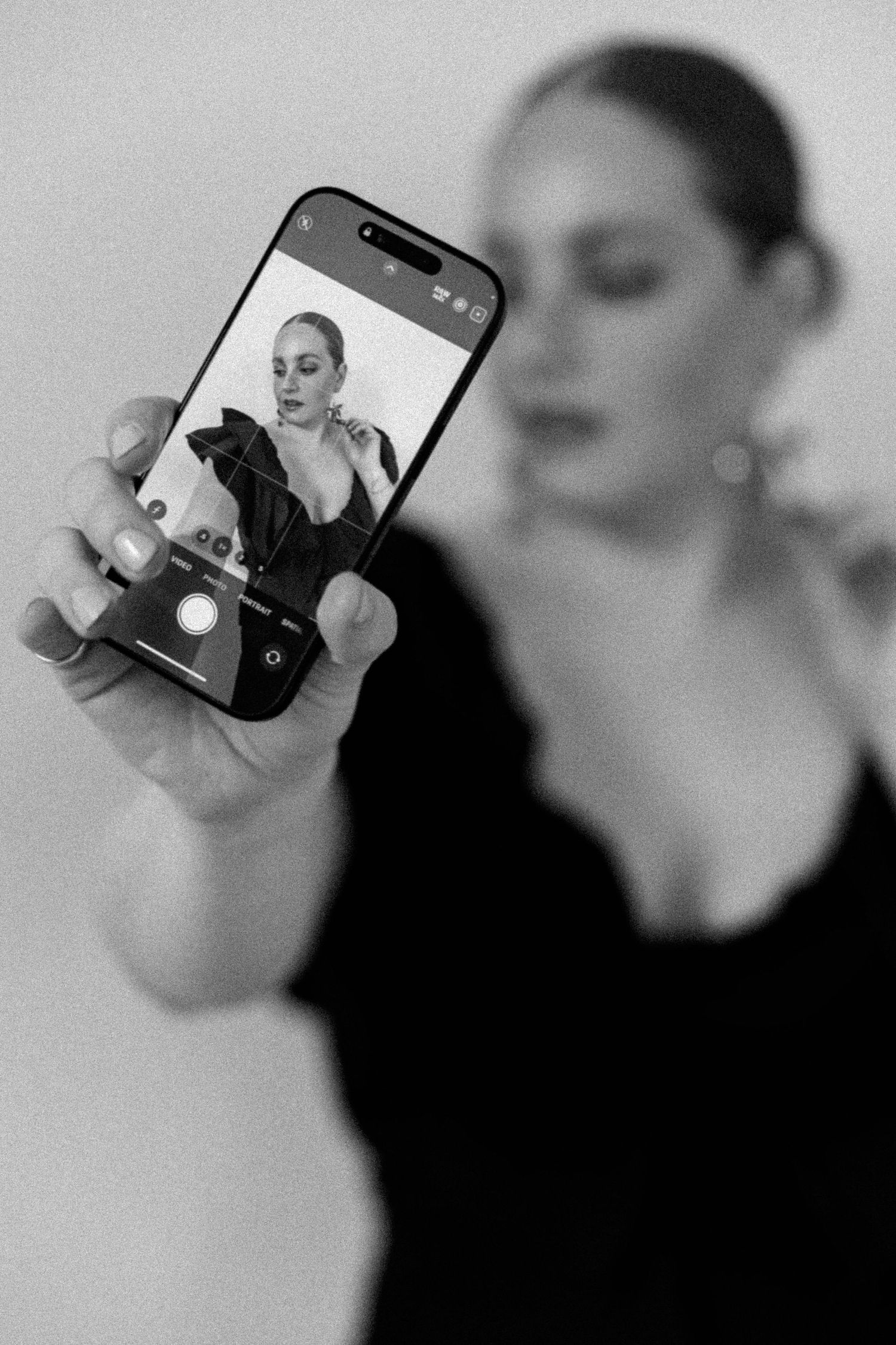 Black and white photo showing iPhone camera screen capturing fashion portrait.