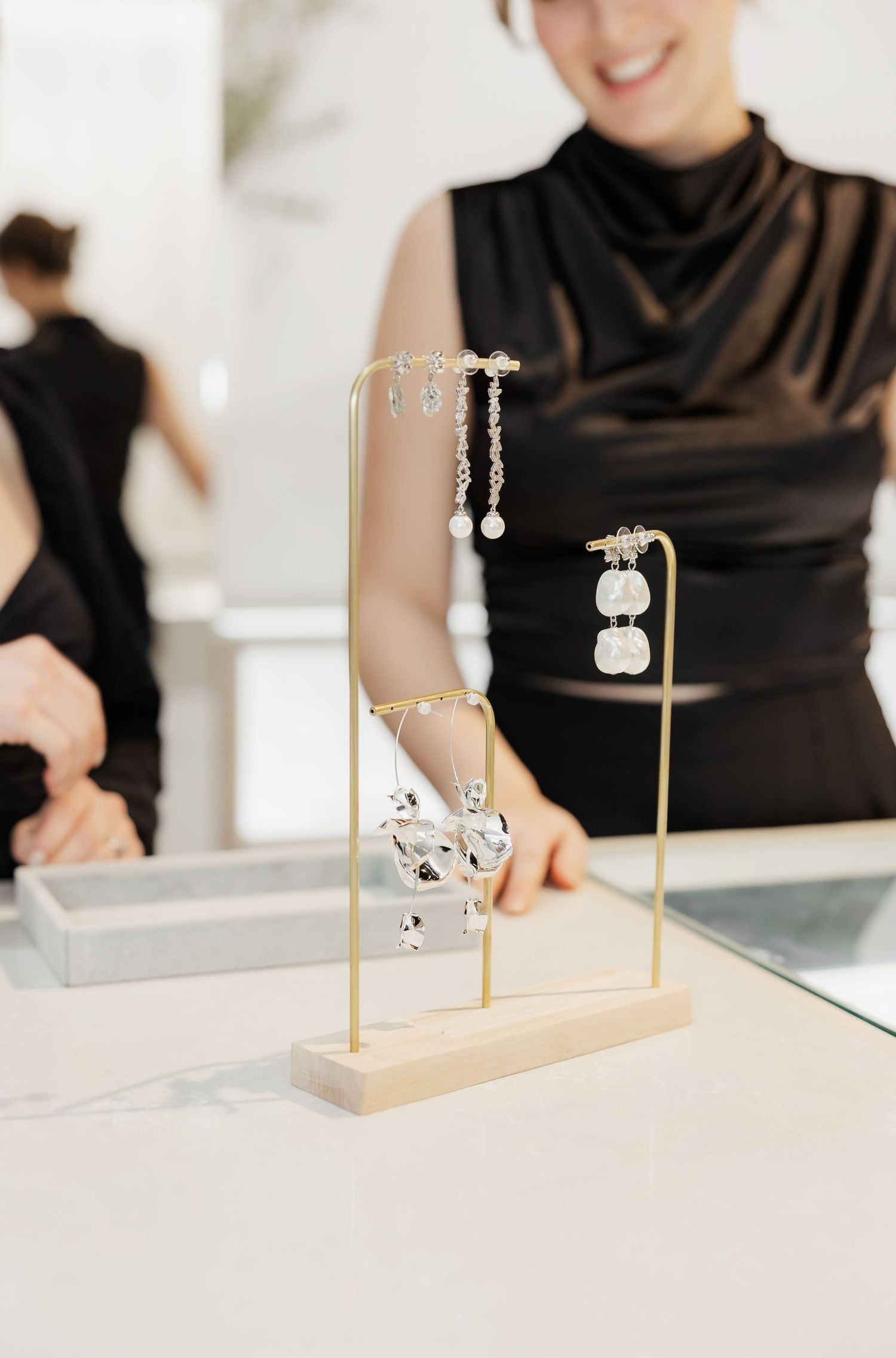 Jewelry display stands showing elegant pieces on a white counter in a retail setting.