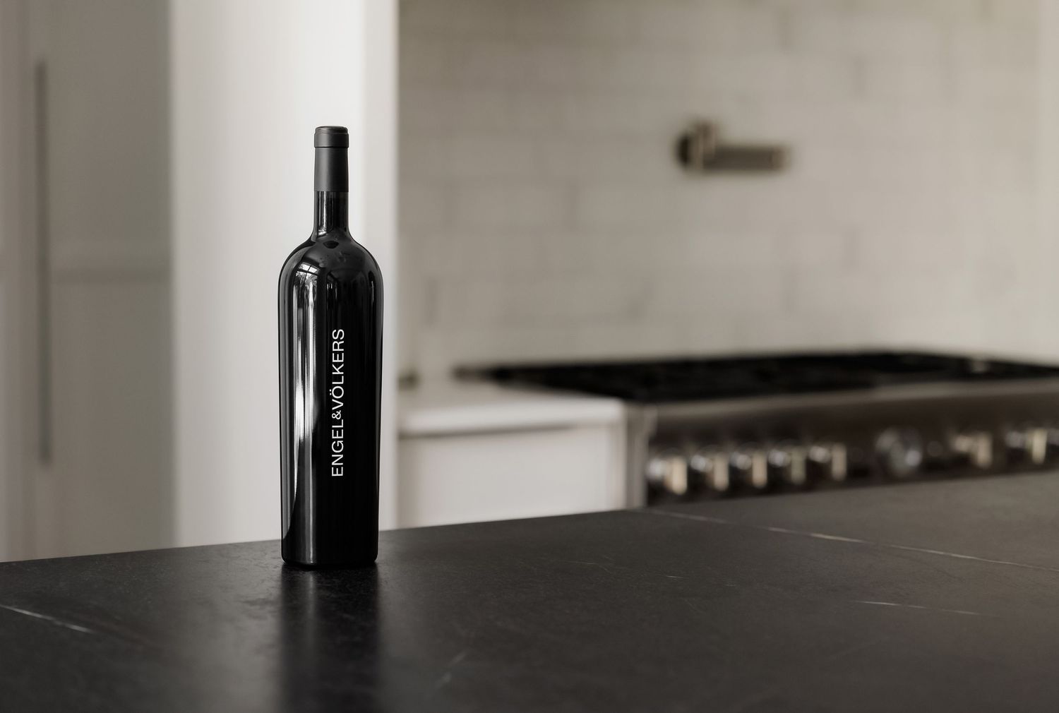 Black wine bottle on sleek marble kitchen countertop in modern interior.
