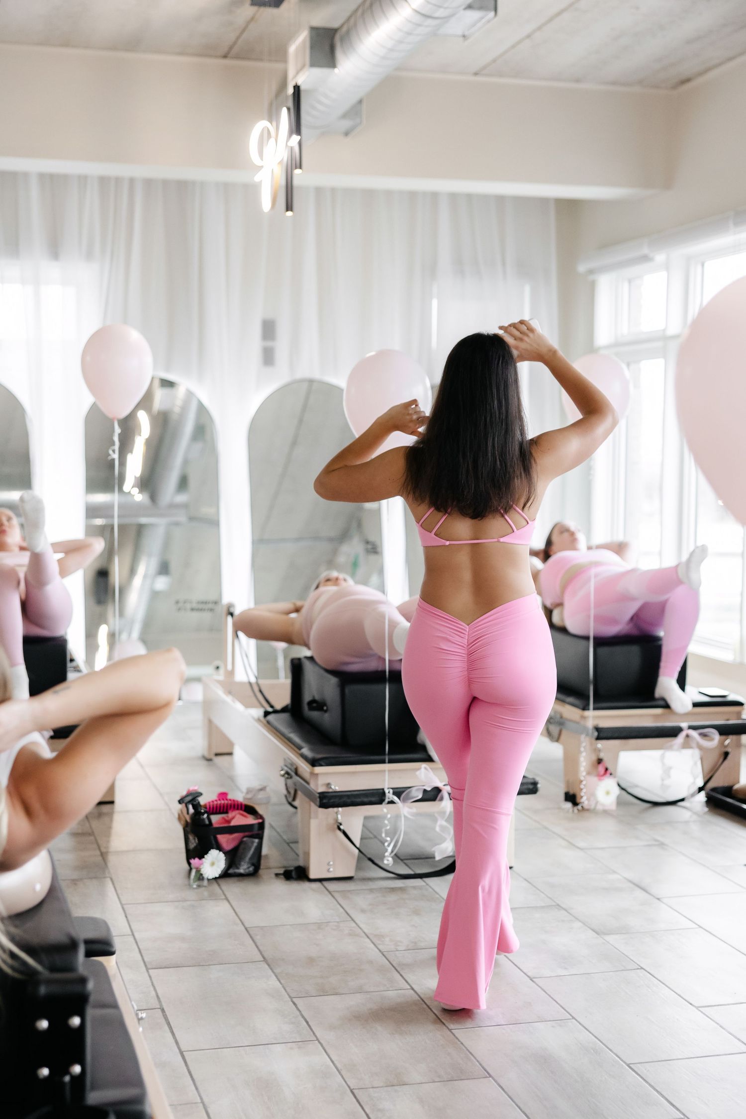 Fitness poses demonstrated on studio floor with pink balloons in background.