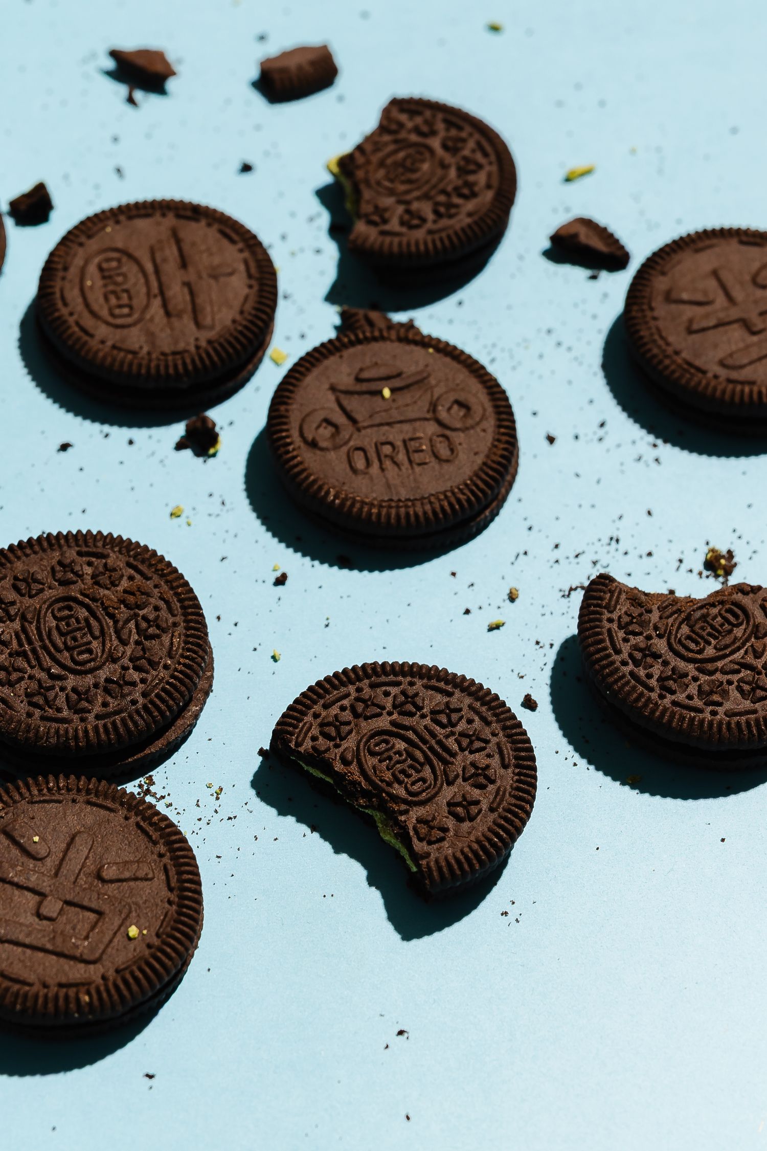 Classic Oreo cookies arranged on a light blue background with crumbs.