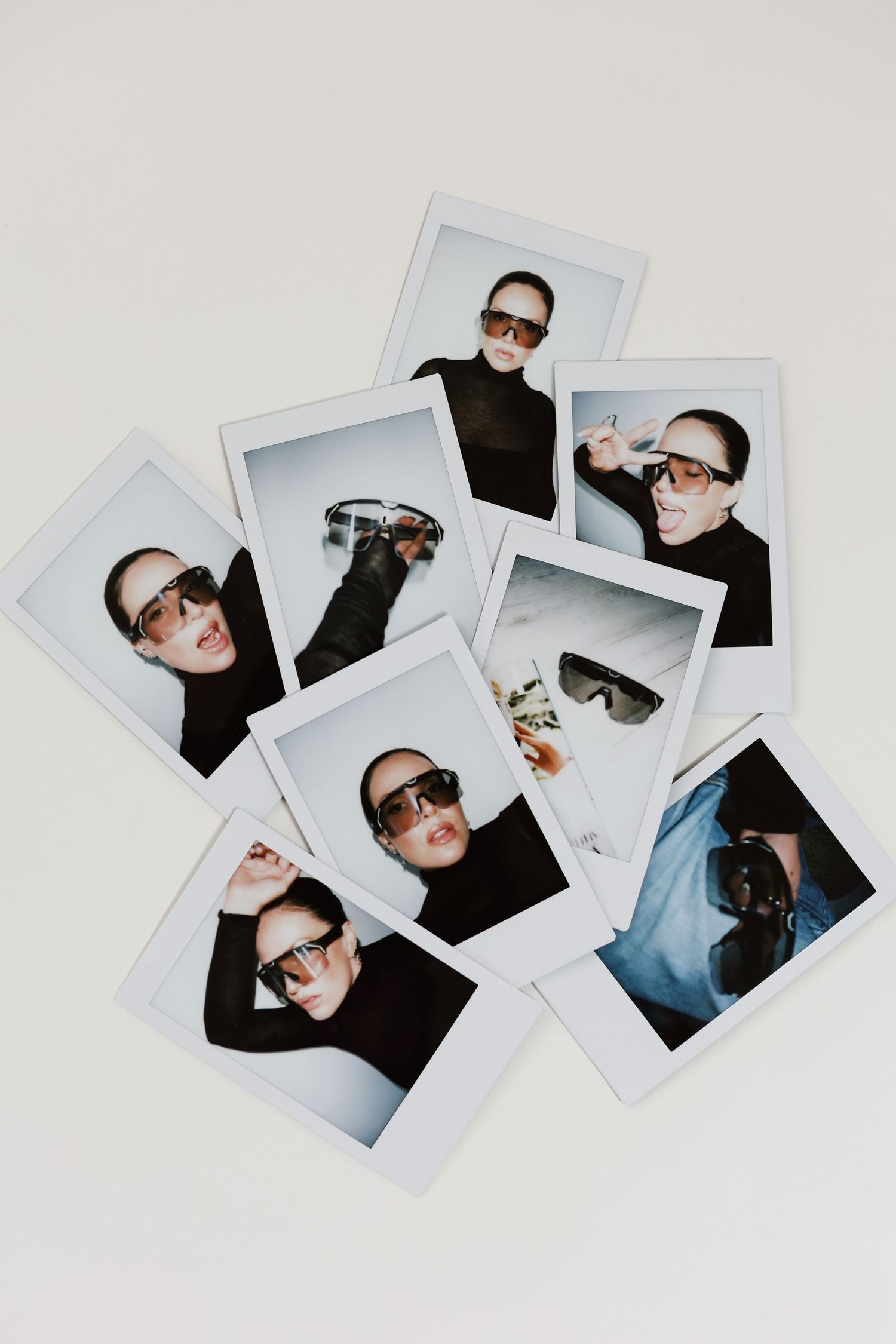 Collection of polaroid fashion photos scattered on white surface showing eyewear campaign.