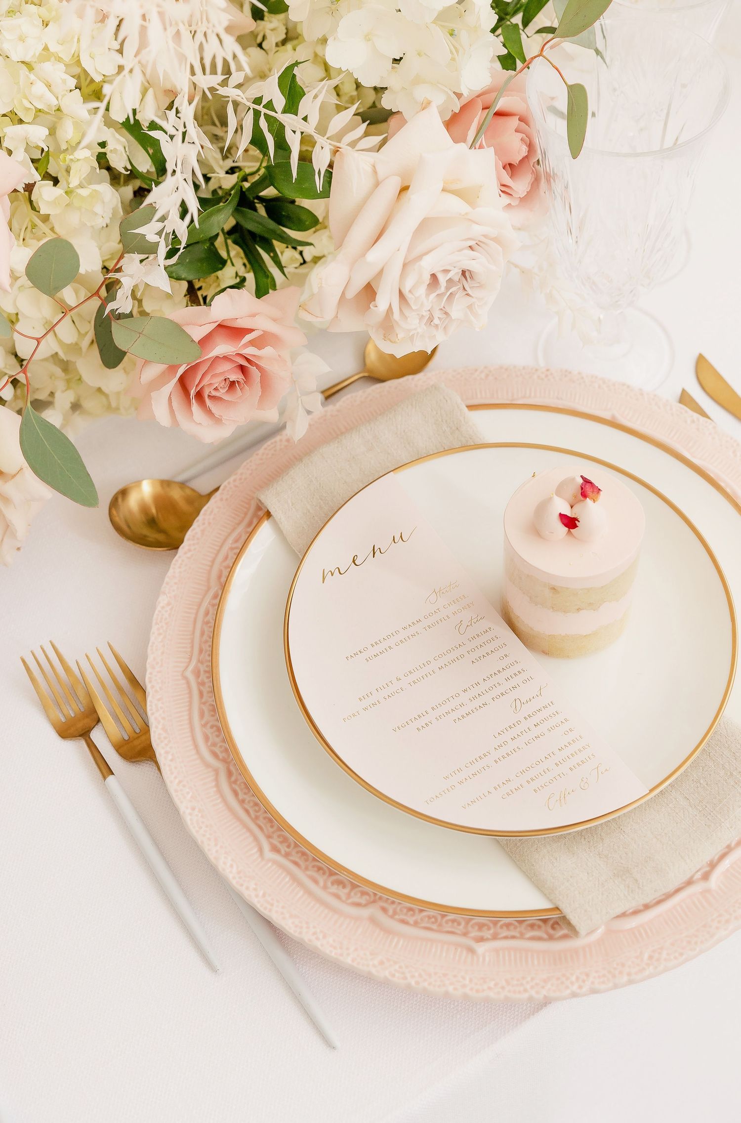 Delicate place setting with blush pink charger plates and fresh floral arrangements.