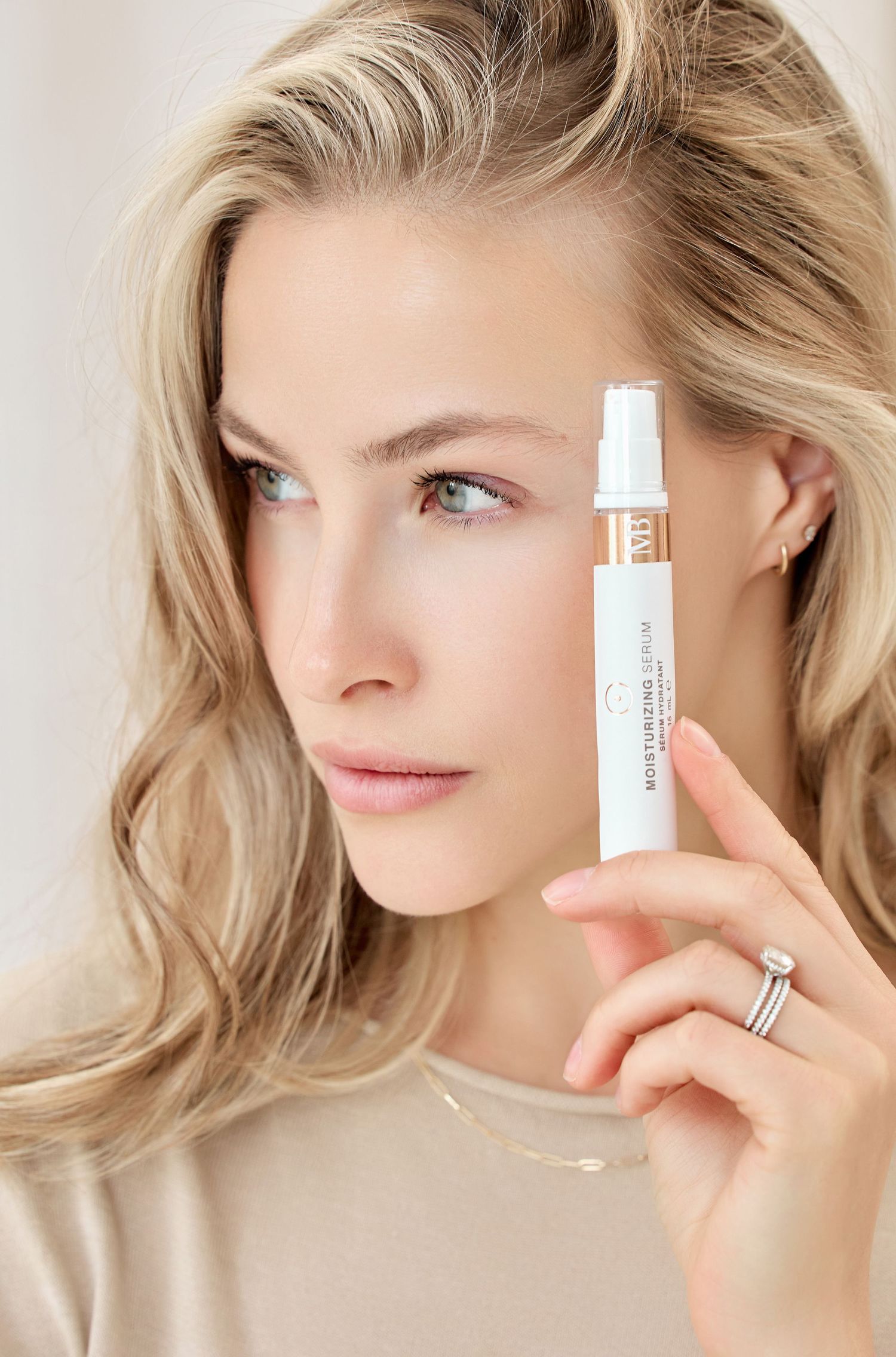 Beauty product demonstration showing white cosmetic containers against neutral background.