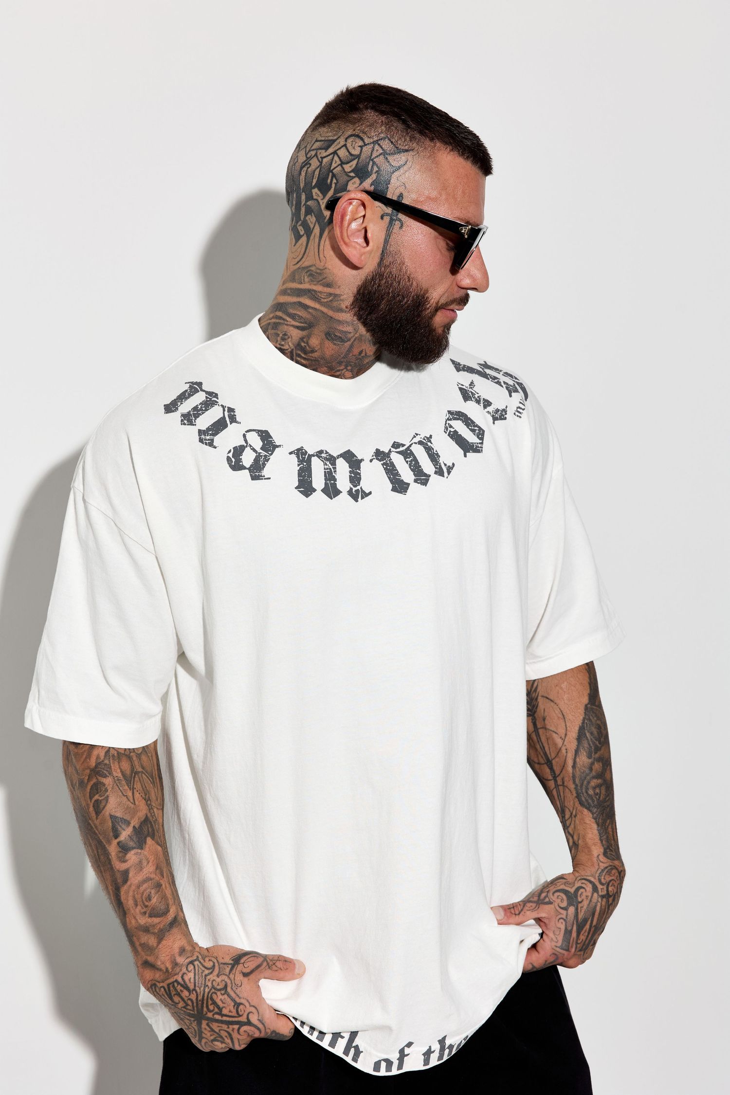 Side view of tattooed model in white t-shirt with gothic text design.