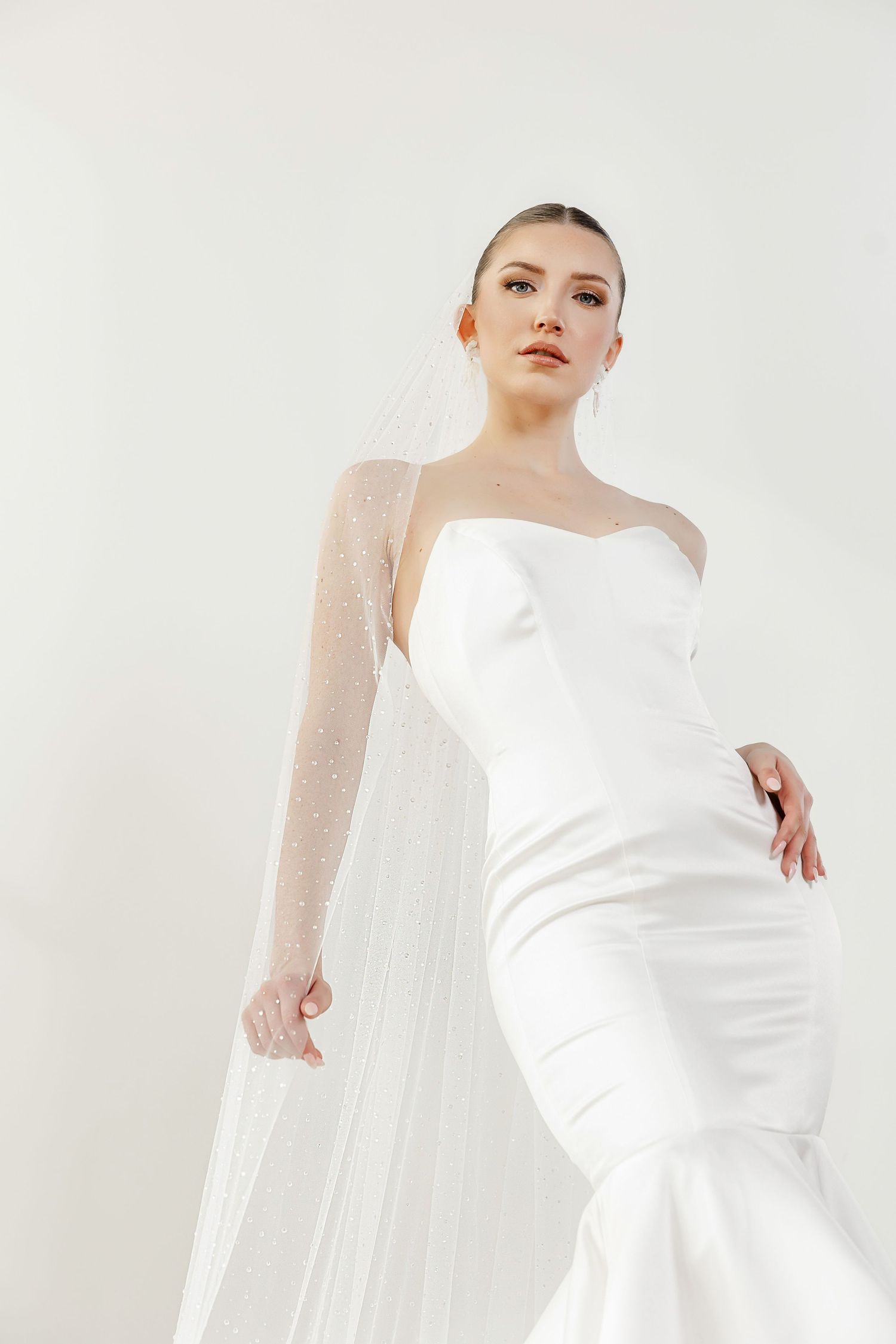 Elegant white bridal gown with sheer sleeves photographed against a light background in multiple angles.