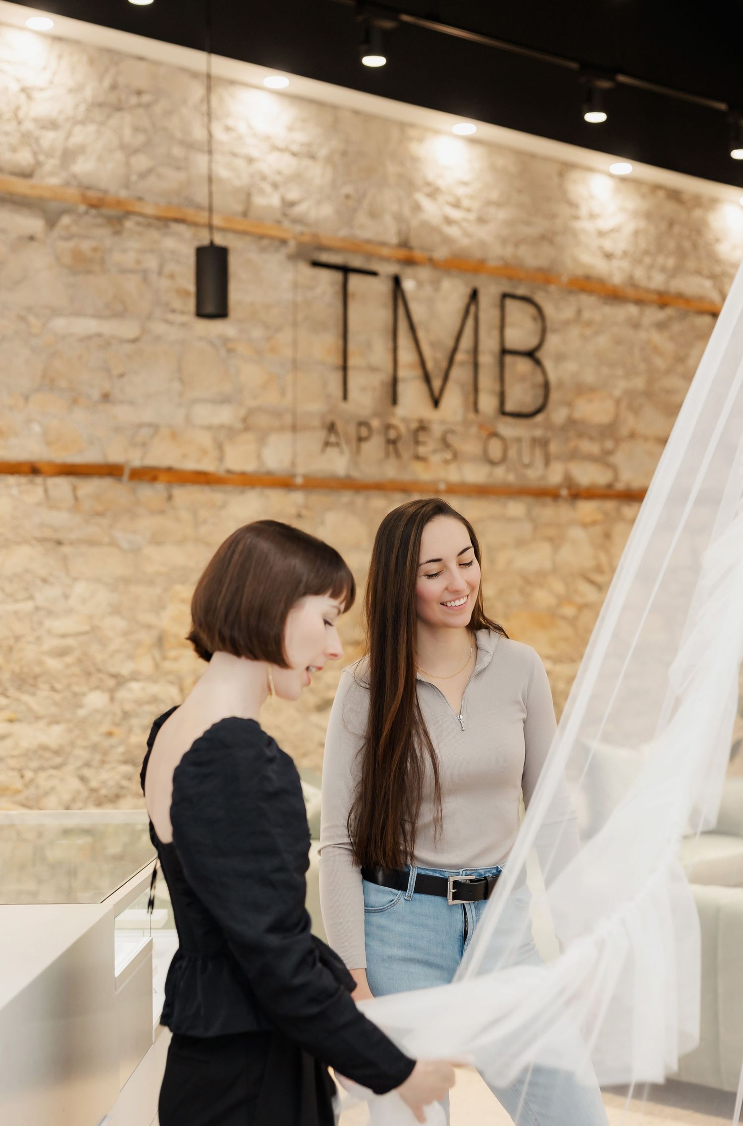 People examining white fabric samples in an upscale retail space with exposed brick walls.