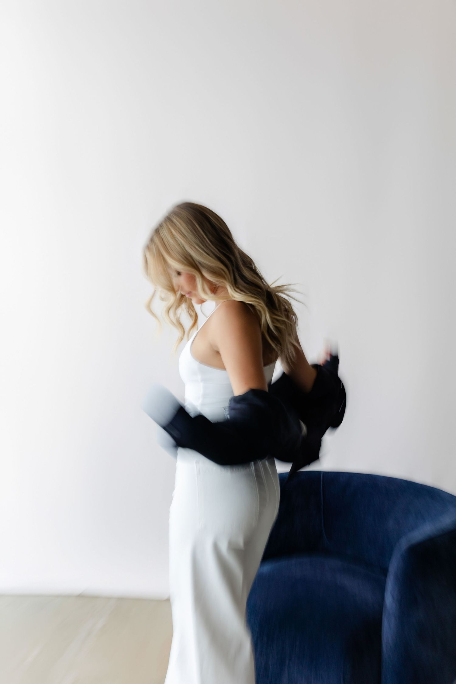 Dynamic fashion pose with flowing movement against white studio backdrop.