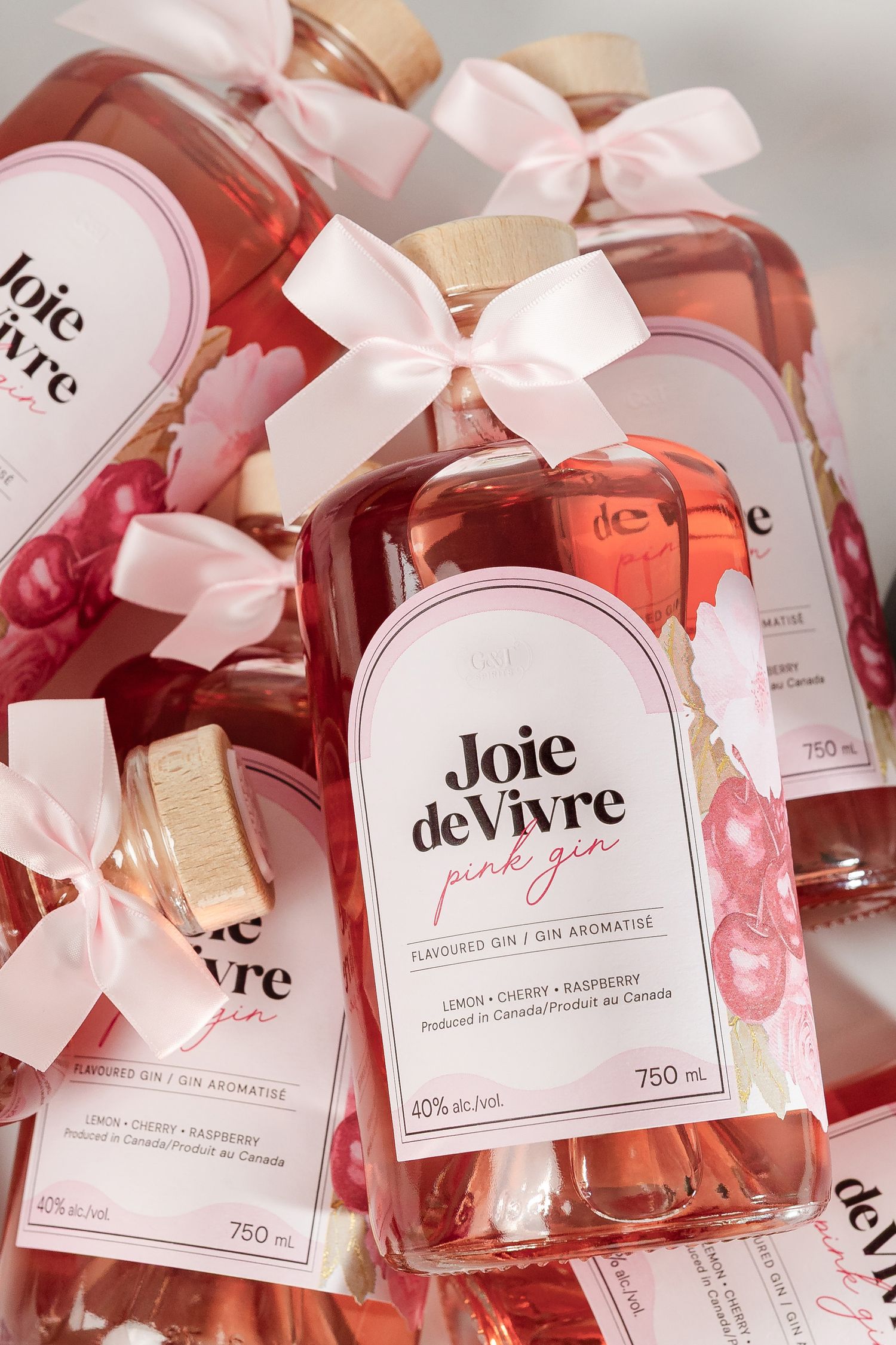 Multiple bottles of rose wine with pink bows and 'Joie de Vivre' branding displayed in a row.