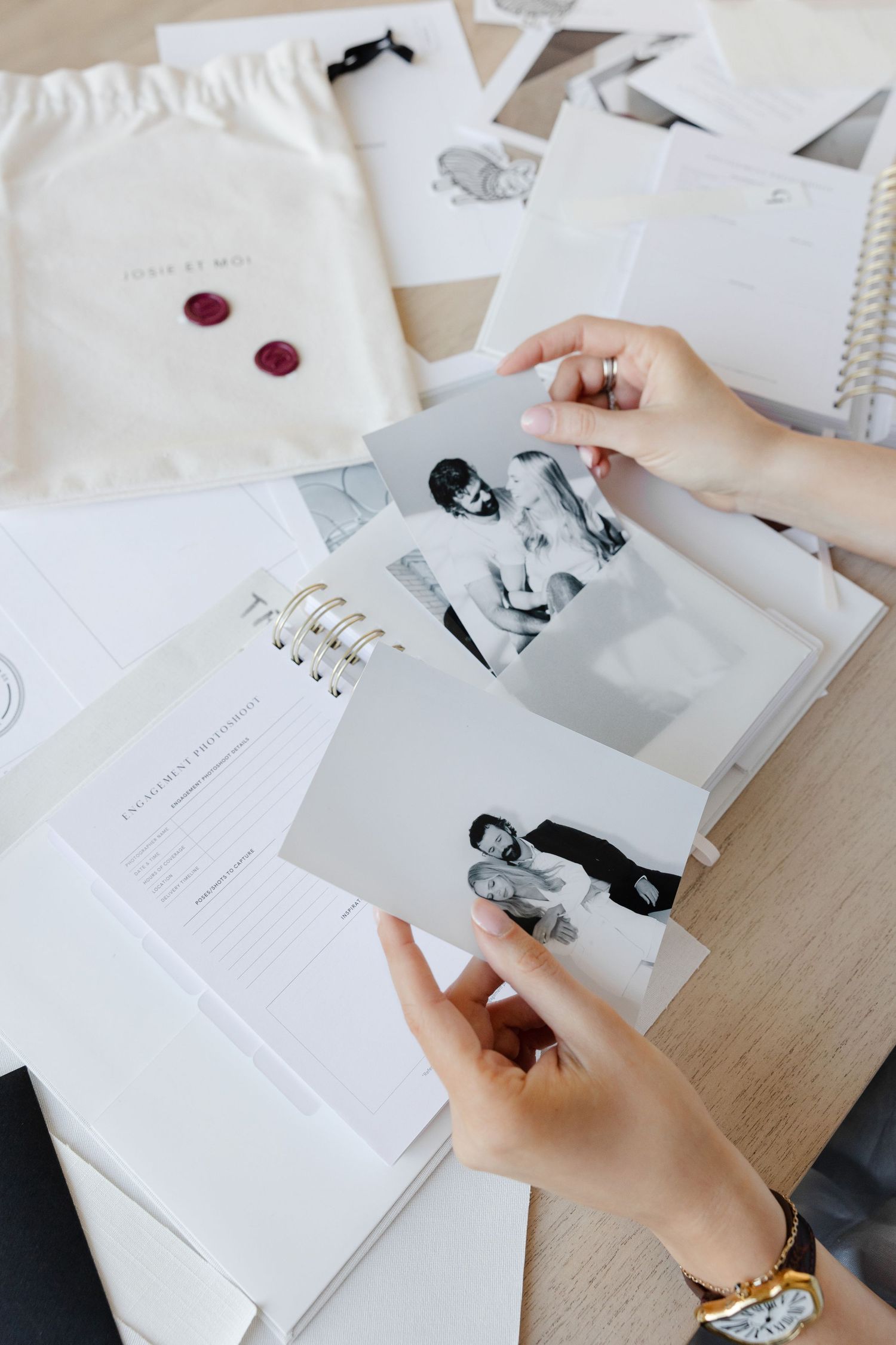 Hands organizing black and white photographs and documents with red wax seals.