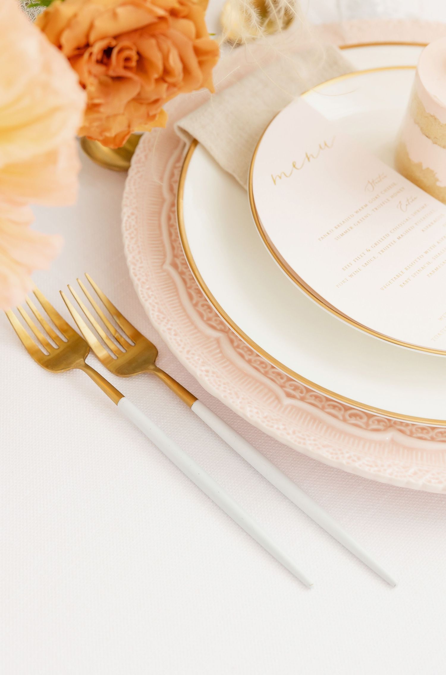 Gold cutlery and white plates with rose gold accents and floral decorations.