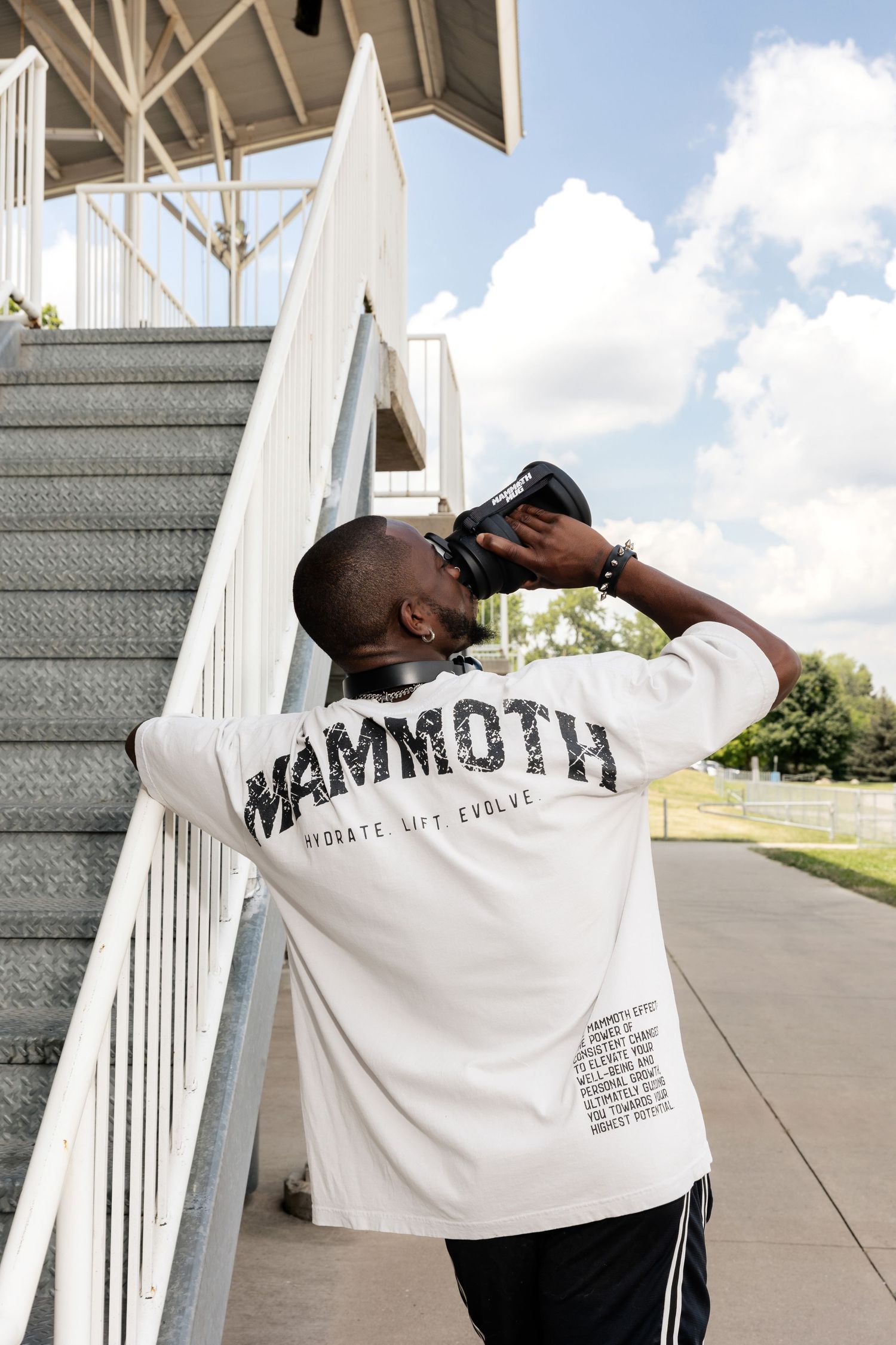 Person wearing Mammoth branded white t-shirt photographed from behind near stairs.