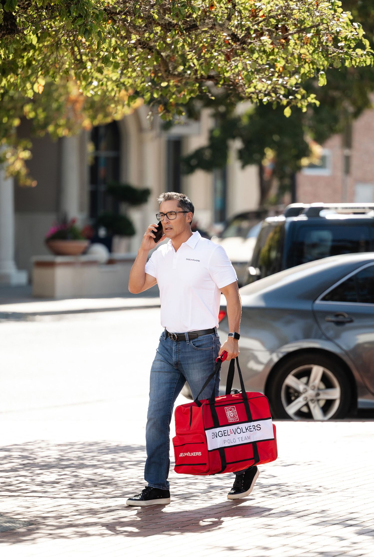 Delivery person crouching with red insulated bags in an urban parking area.
